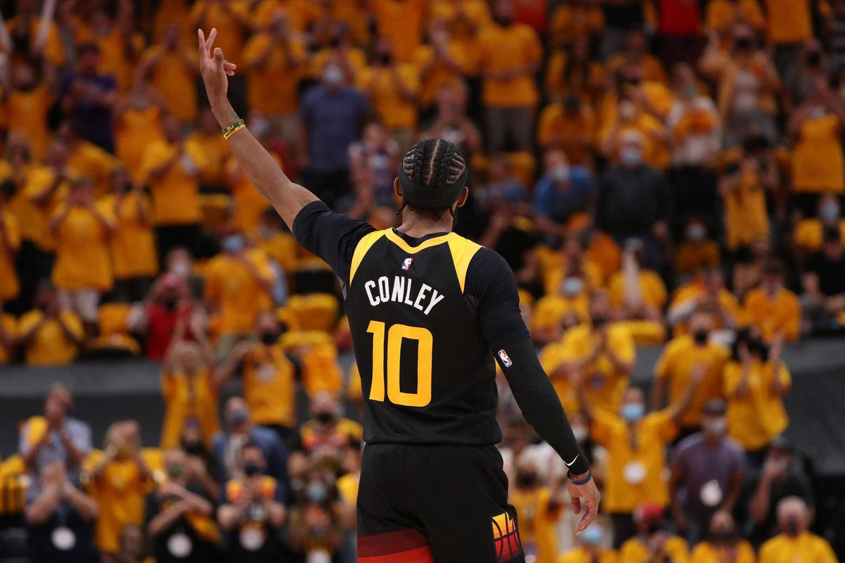 mike conley 桌布 壁紙 — 一名身穿黑色和黃色球衣、印有Conley名字和10號的籃球運動員向一群身穿黃色衣服的球迷揮手。
