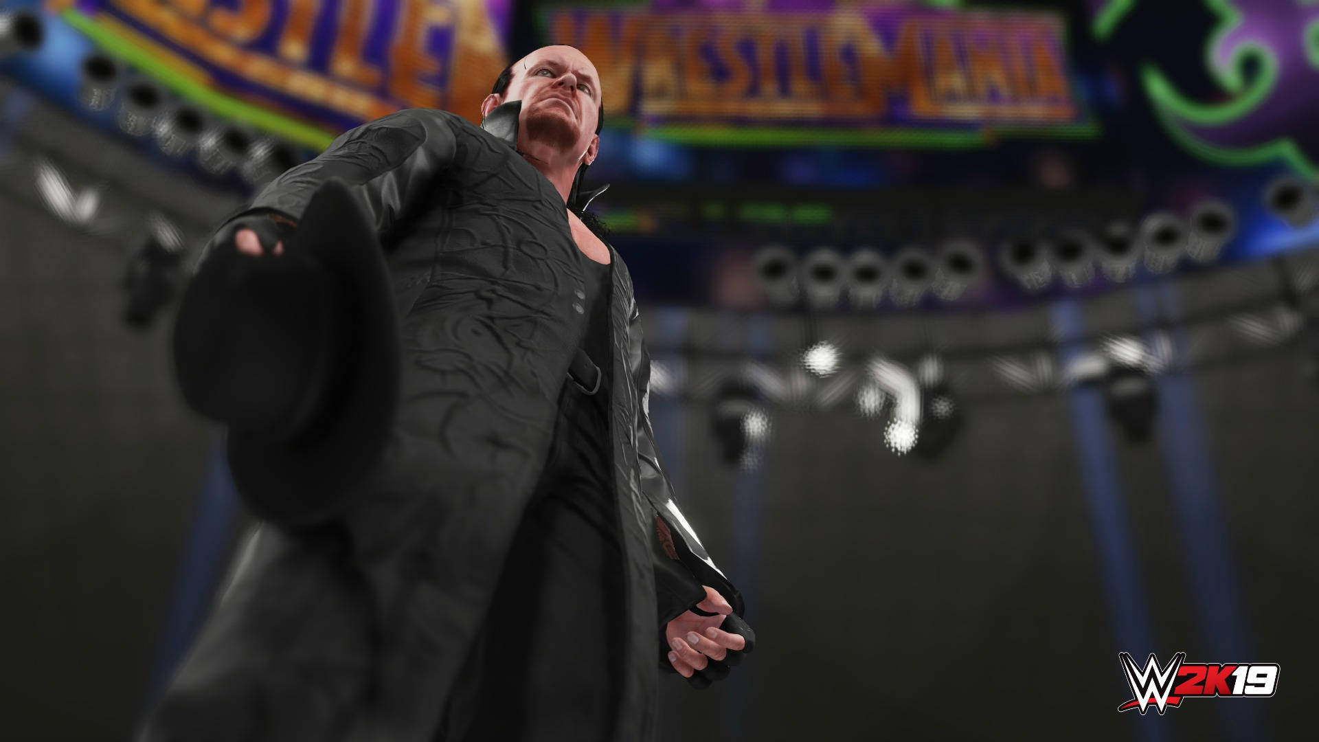 Undertaker 桌布 壁紙 — 一名身穿黑色外套和高帽的威嚇摔角手在場館燈光下戲劇性地站立，背後有發光的 'WRESTLEMANIA' 標誌。