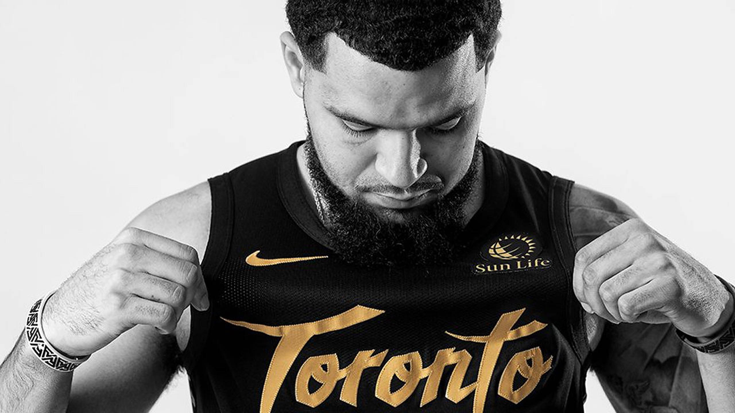 Fred Vanvleet 桌布 壁紙 — 一名身穿黑色多倫多球衣、金色字樣的籃球運動員，用力拉緊布料，專注地向下看。