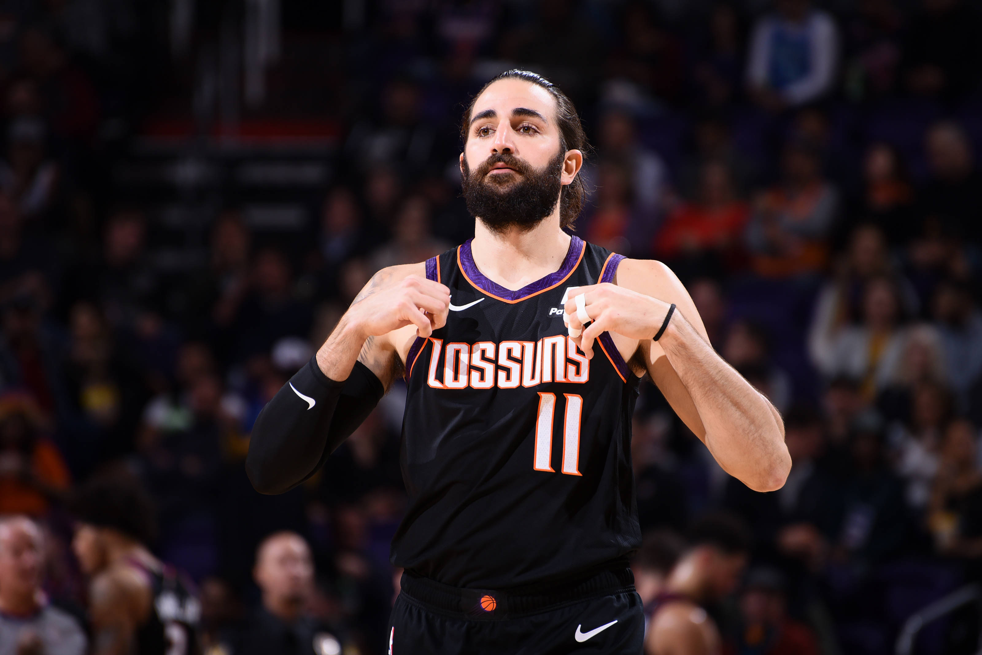 Ricky Rubio 桌布 壁紙 — 一名身穿黑色太陽隊11號球衣的籃球運動員在場館燈光下於比賽中激烈地做手勢。