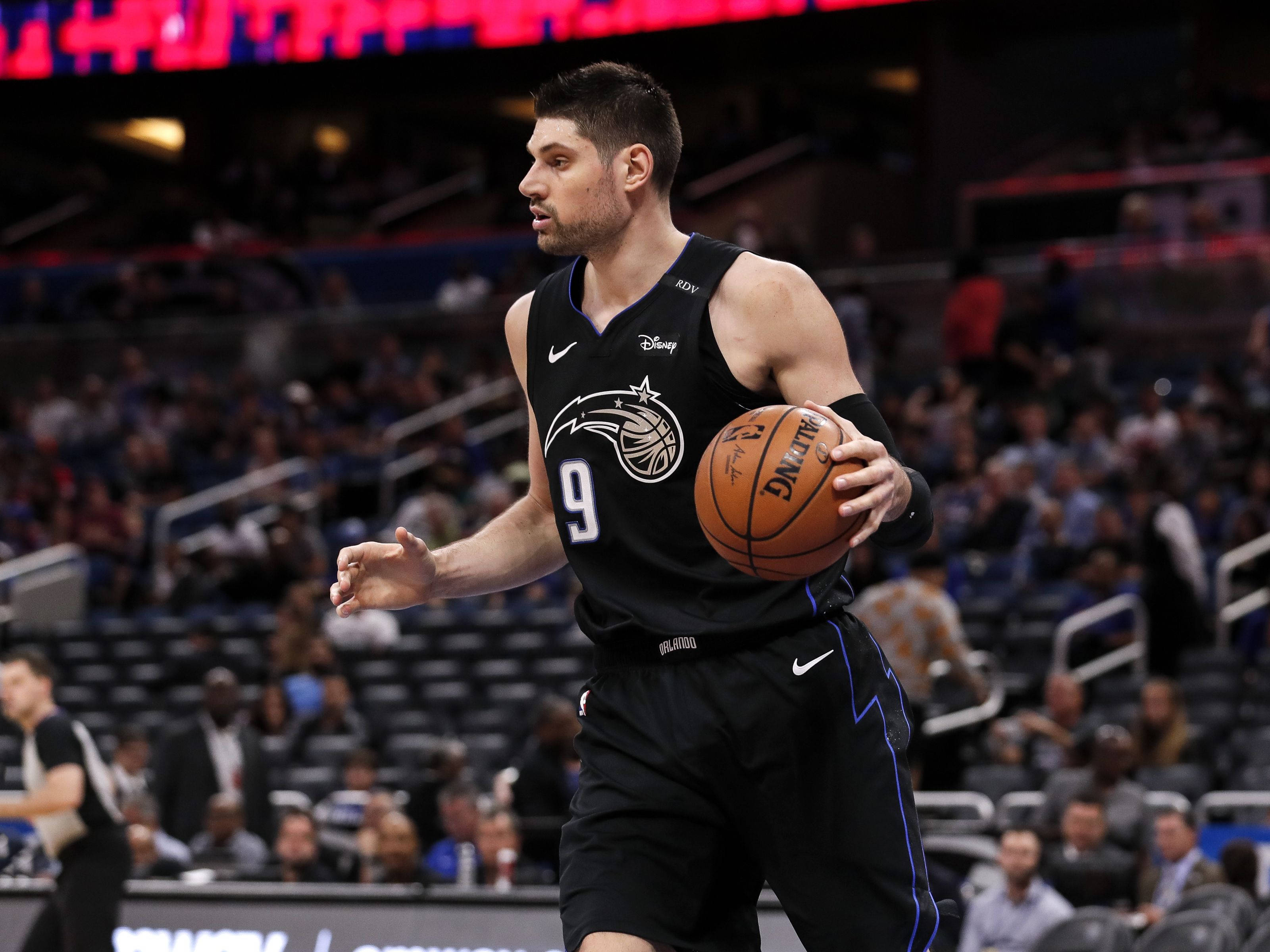 NBA 桌布 壁紙 — 一名身穿黑色奧蘭多魔術隊球衣的籃球運動員在明亮的場館燈光下於比賽中運球。