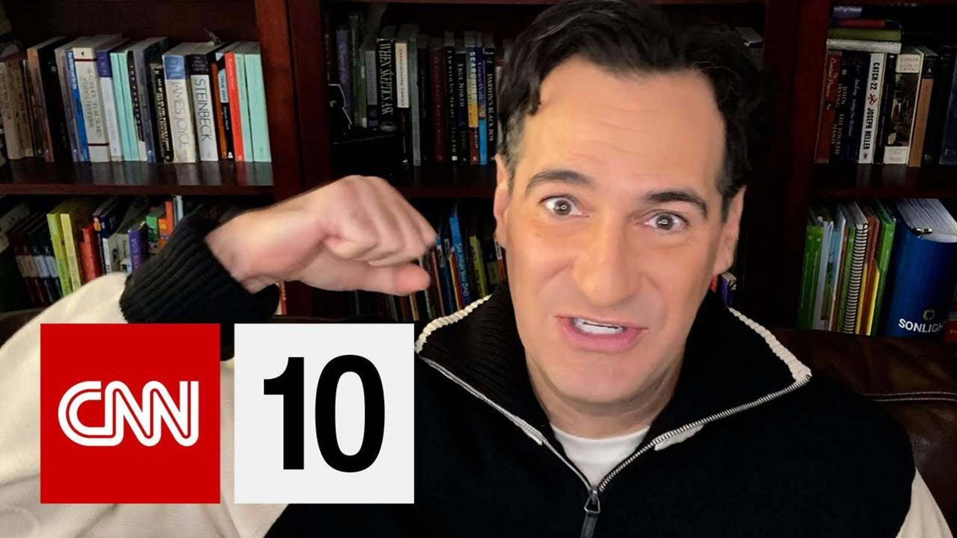 tv 桌布 壁紙 — 一名身穿黑色拉鍊外套的男子在帶有CNN 10標誌疊加的書架前做出握拳手勢。