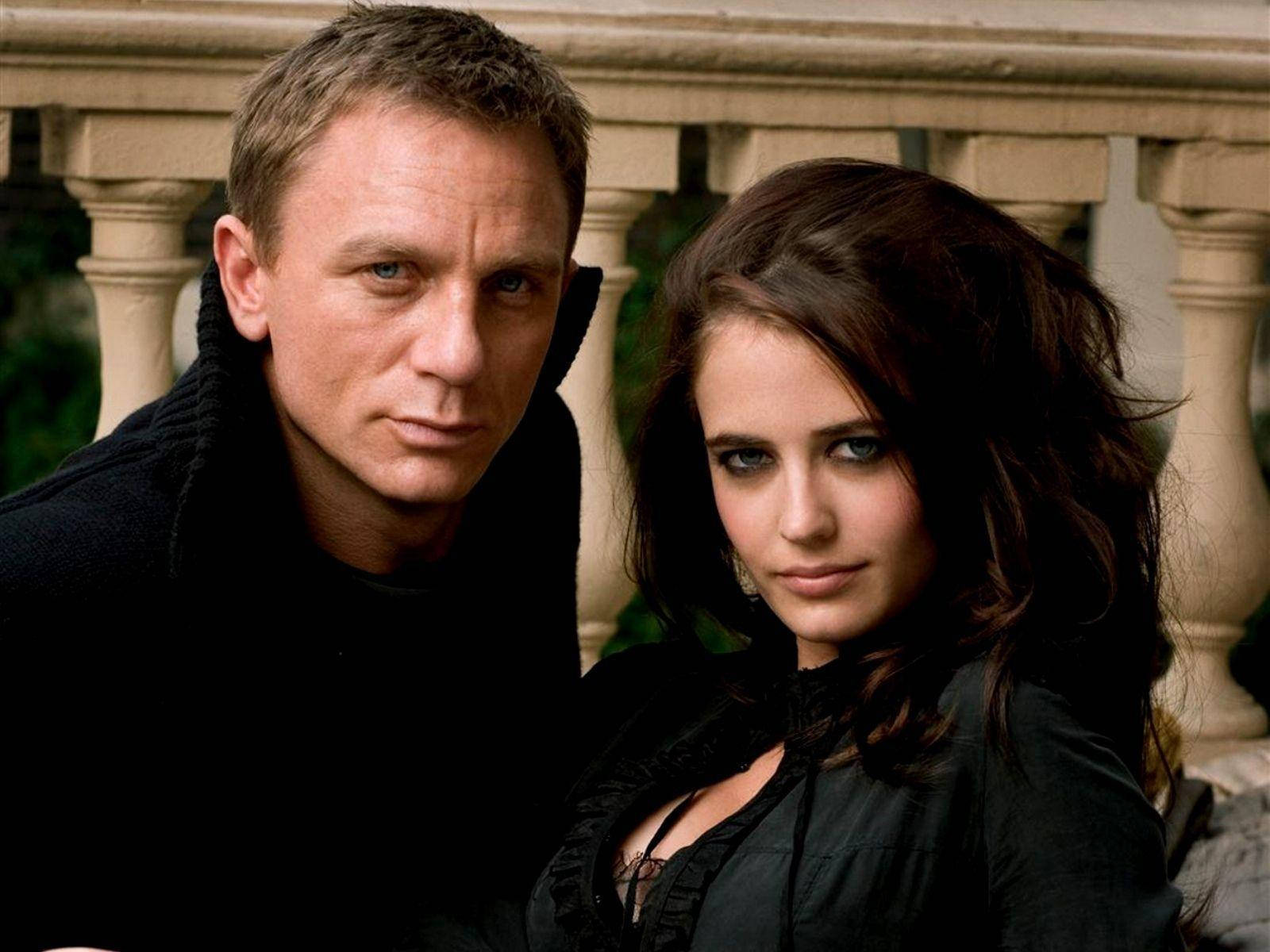 Daniel Craig 桌布 壁紙 — 一名身穿黑色服裝的男女緊靠在一起，站在石欄杆前，身後有綠植。