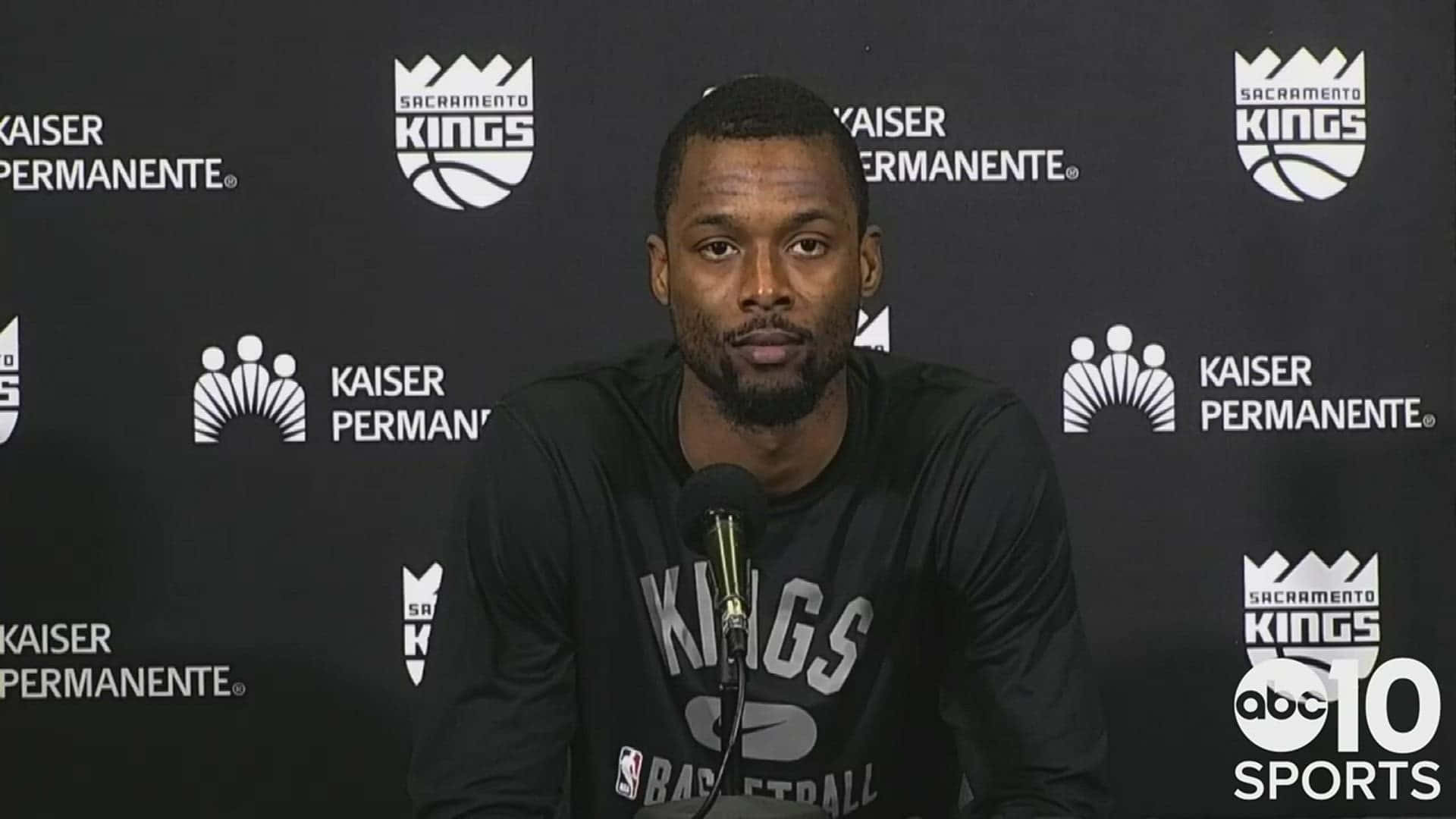 NBA 桌布 壁紙 — 一名身穿黑色沙加緬度國王隊球衣的籃球運動員在記者會上對著麥克風講話，背景有品牌標誌。