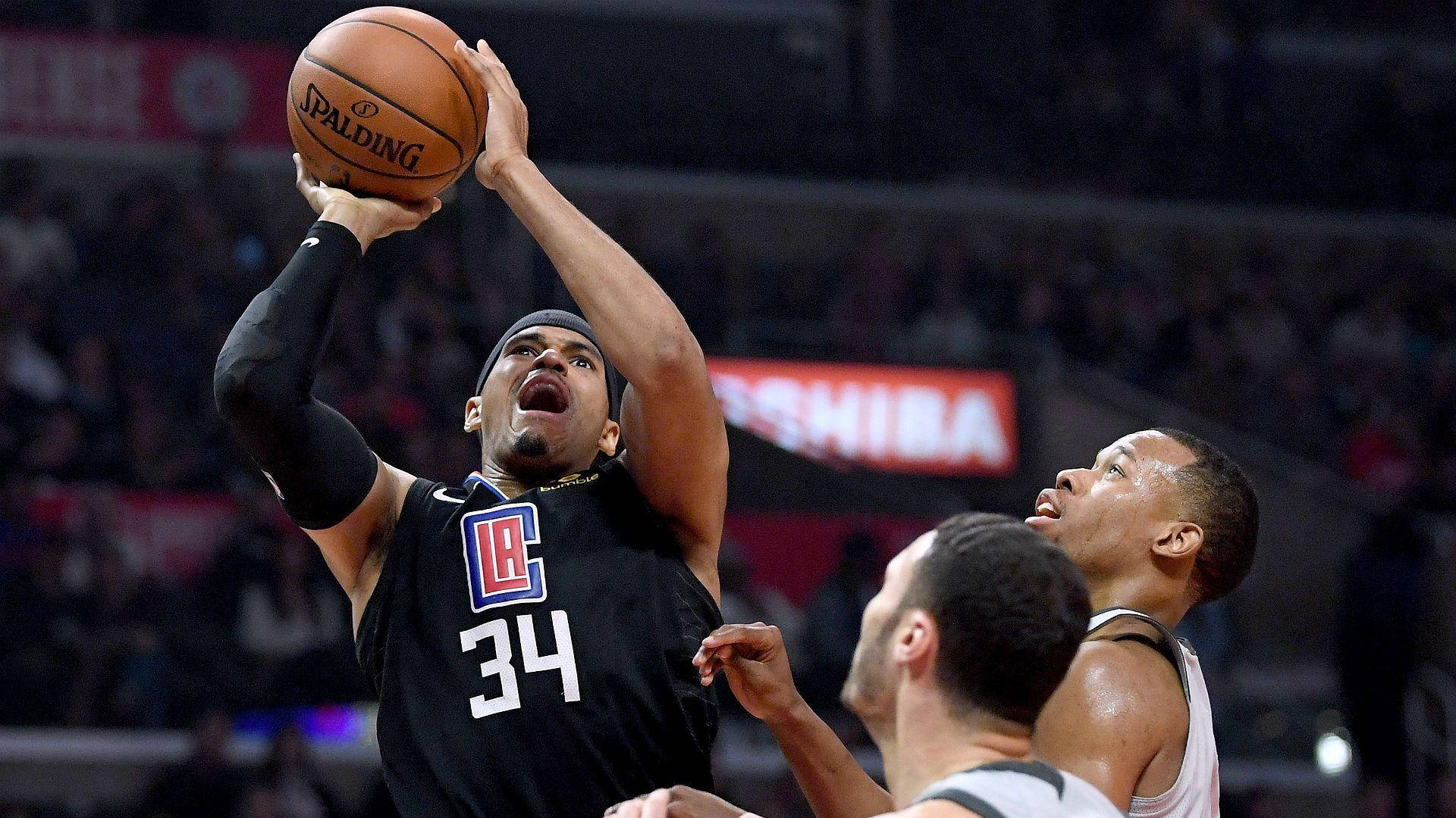 NBA 桌布 壁紙 — 一名身穿黑色洛杉磯快艇隊球衣的籃球運動員跳起投擲Spalding籃球，防守球員在緊張的比賽中逼近。