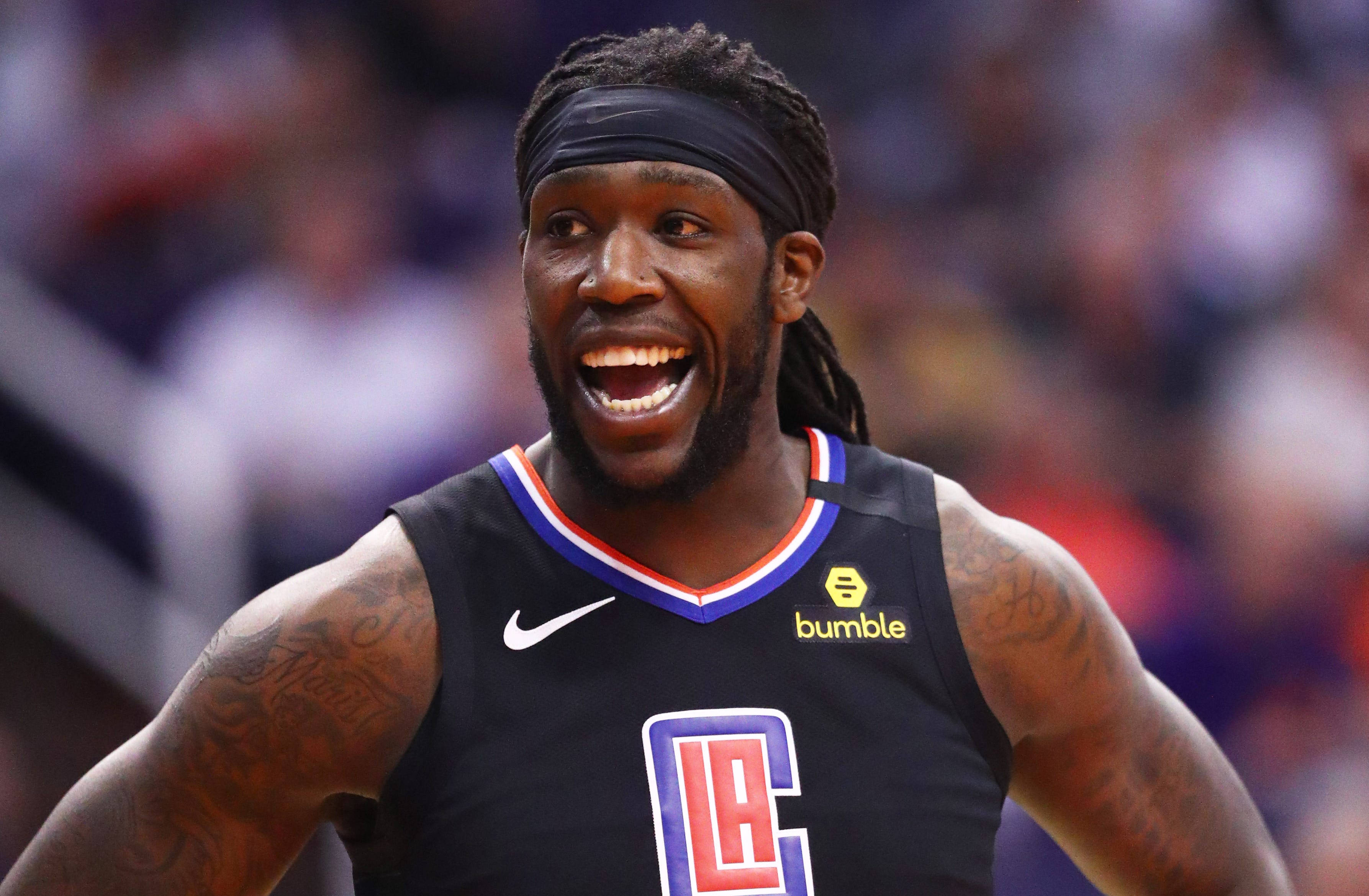 montrezl harrell 桌布 壁紙 — 一名身穿黑色洛杉磯快艇隊球衣的籃球運動員在比賽中大笑，手臂上的刺青清晰可見。
