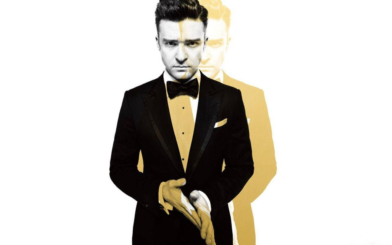 justin timberlake 桌布 壁紙 — 一名身穿黑色燕尾服、搭配金色裝飾和白色手套的男子，站在純白背景前，身後有金色剪影。