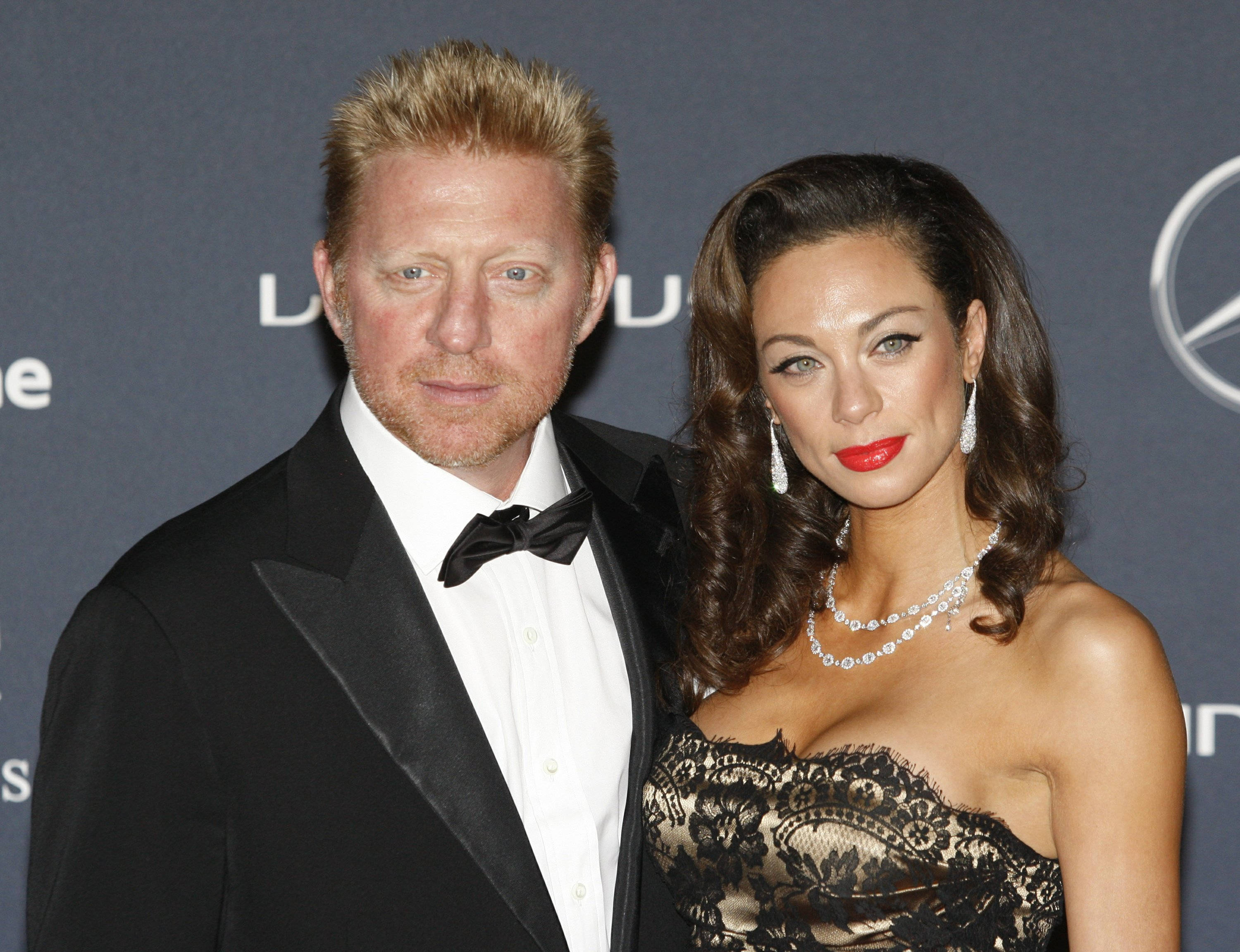 Boris Becker 桌布 壁紙 — 一名身穿黑色燕尾服的男士和一名身穿黑色蕾絲裙的女士在品牌背景前於正式活動中一起擺姿勢。
