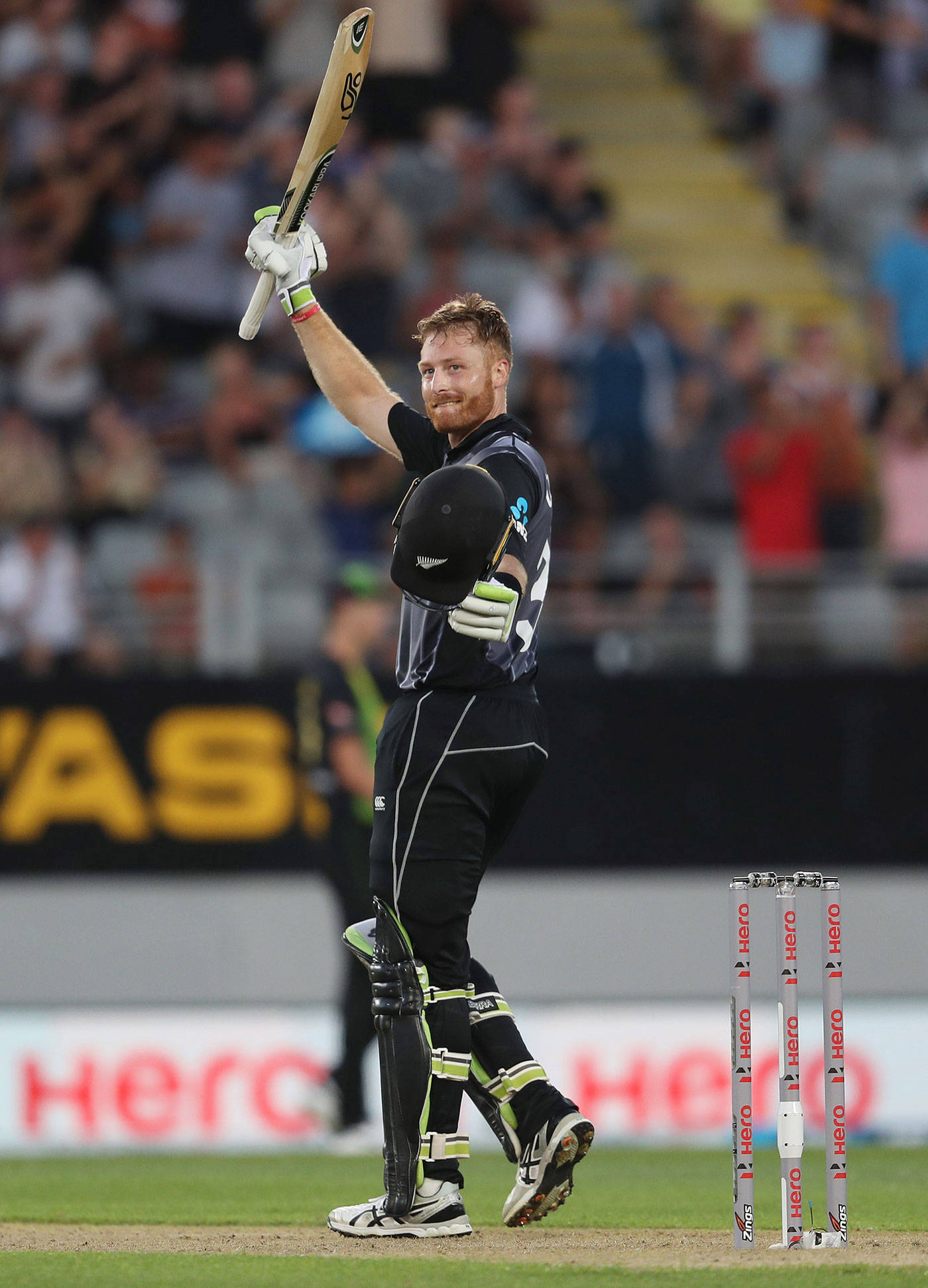 martin guptill 桌布 壁紙 — 一名身穿黑色球衣的板球運動員在燈光球場上高舉球棒慶祝。