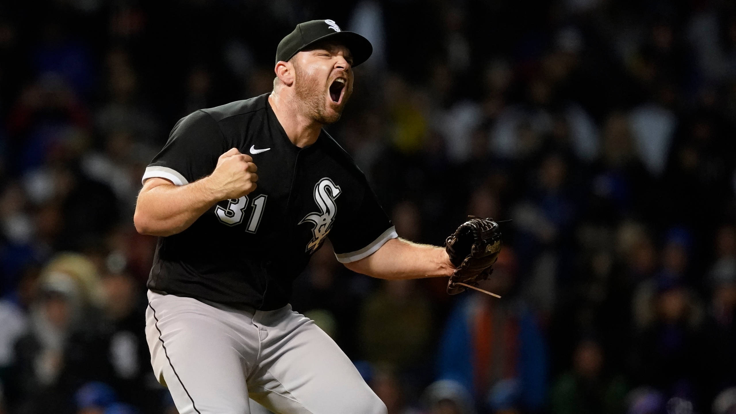 Chicago White Sox 桌布 壁紙 — 一名身穿黑色球衣的棒球投手在球場燈光下握緊拳頭、伸出手套，發出勝利的怒吼。