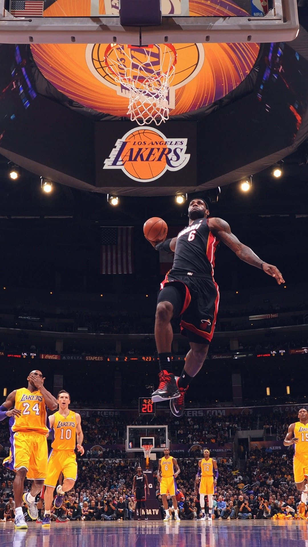 Basketball Aesthetic 桌布 壁紙 — 一名身穿黑色球衣的籃球運動員在湖人隊比賽中飛向籃框，下方球迷歡呼。