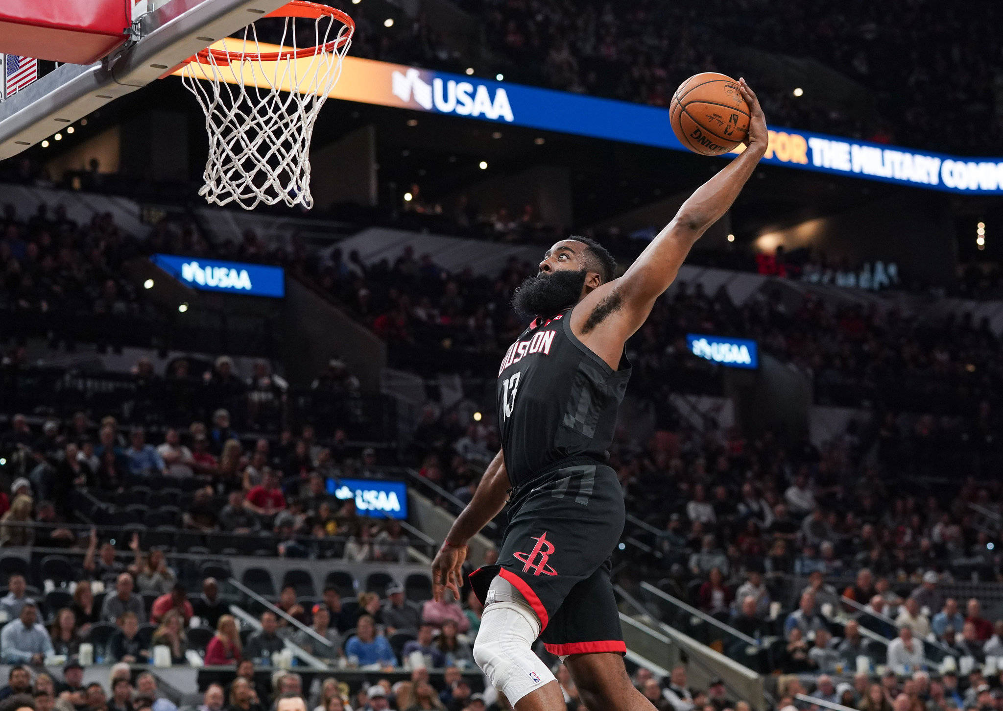 James Harden 桌布 壁紙 — 一名身穿黑色球衣的籃球運動員在燈光璀璨的球場上扣籃，全場觀眾座無虛席。
