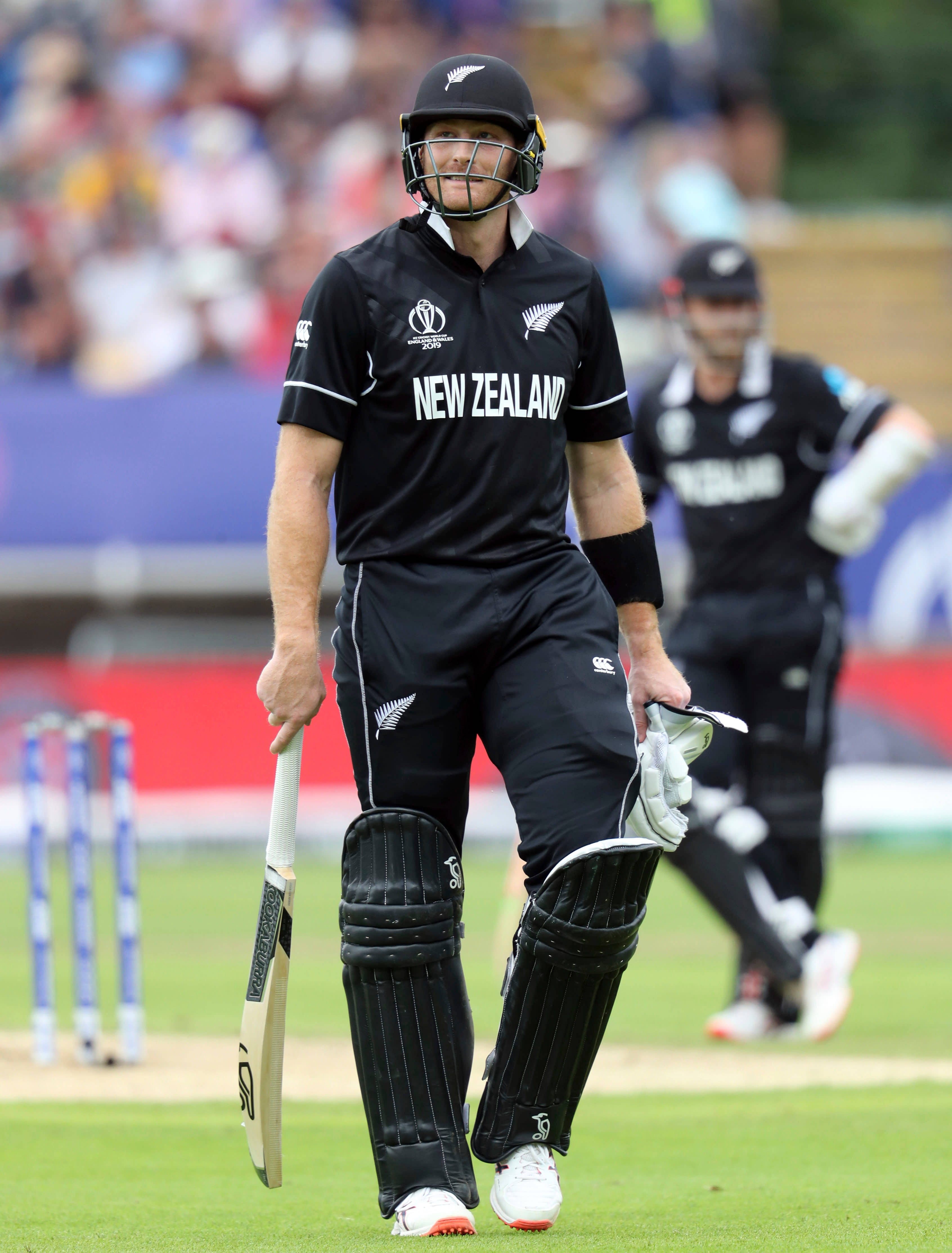 martin guptill 桌布 壁紙 — 一名身穿黑色球衣的紐西蘭板球運動員在比賽後手持球棒和手套離開球場。