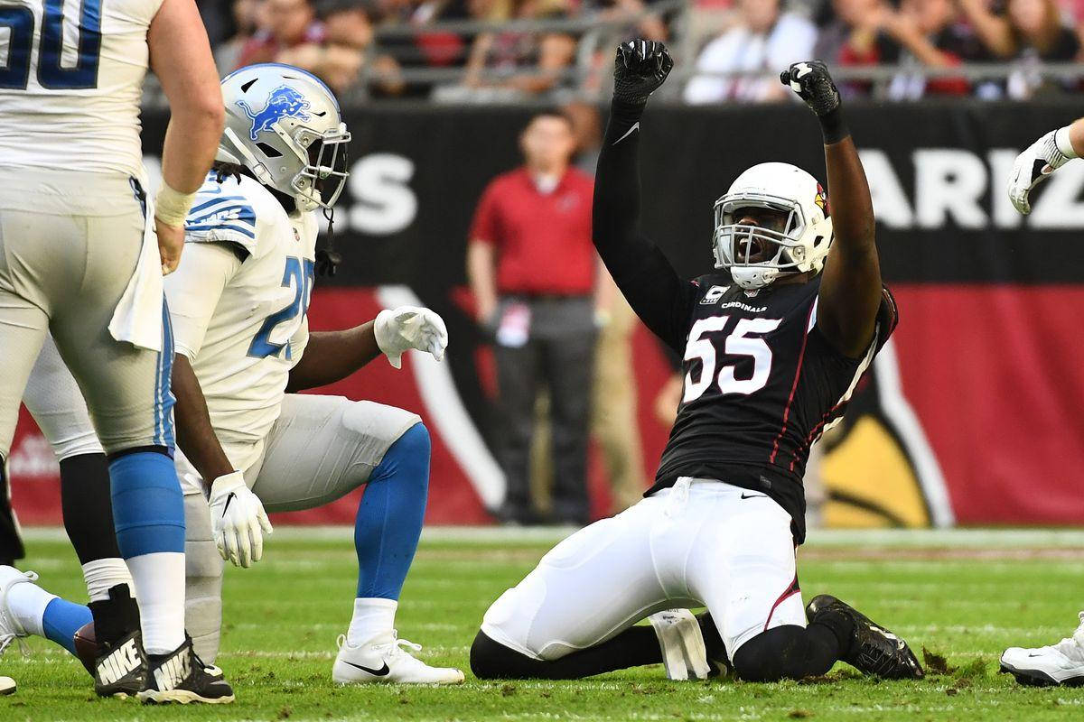 Arizona Cardinals 桌布 壁紙 — 一名身穿黑色球衣的足球員跪在草地上，高舉雙臂慶祝勝利，隊友和觀眾在旁觀看。