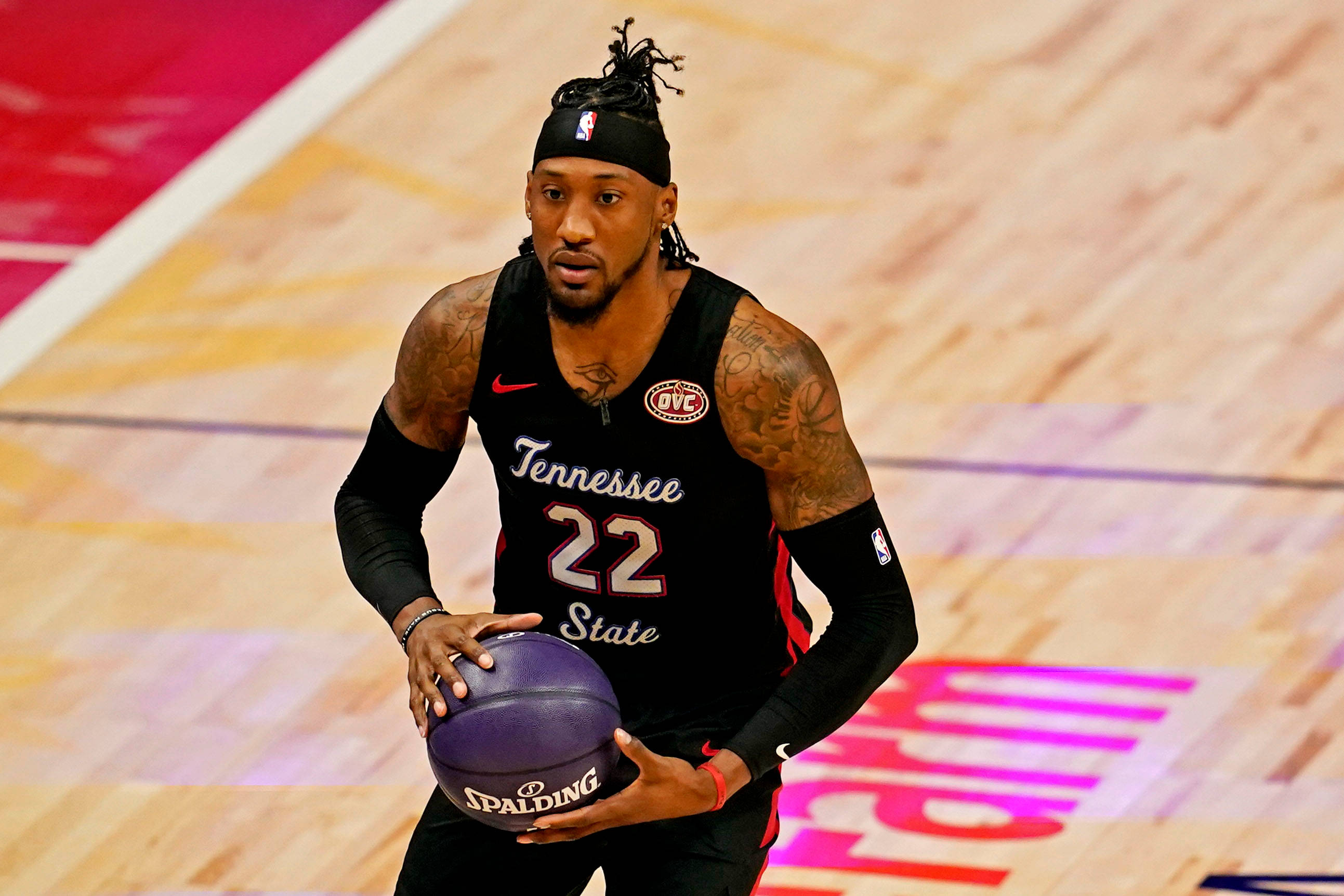 robert covington 桌布 壁紙 — 一名身穿黑色田納西州立大學球衣的籃球運動員，在燈光明亮的球場上運著一個紫色的Spalding籃球。