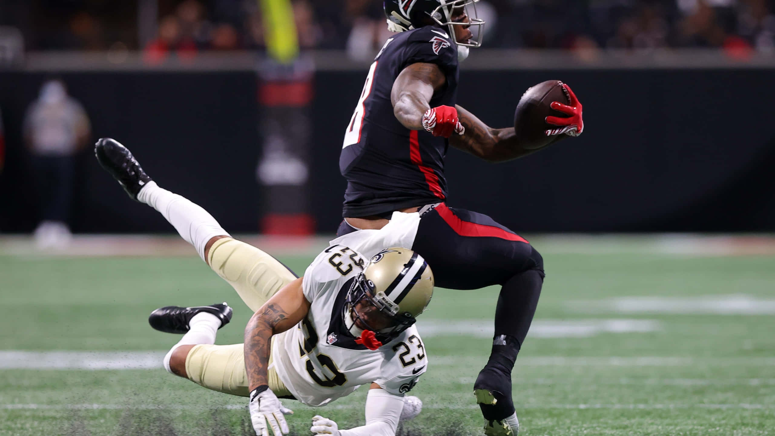 New Orleans Saints 桌布 壁紙 — 一名身穿黑色的足球員在激烈的夜間比賽中躍過一名身穿白色的飛身防守球員。