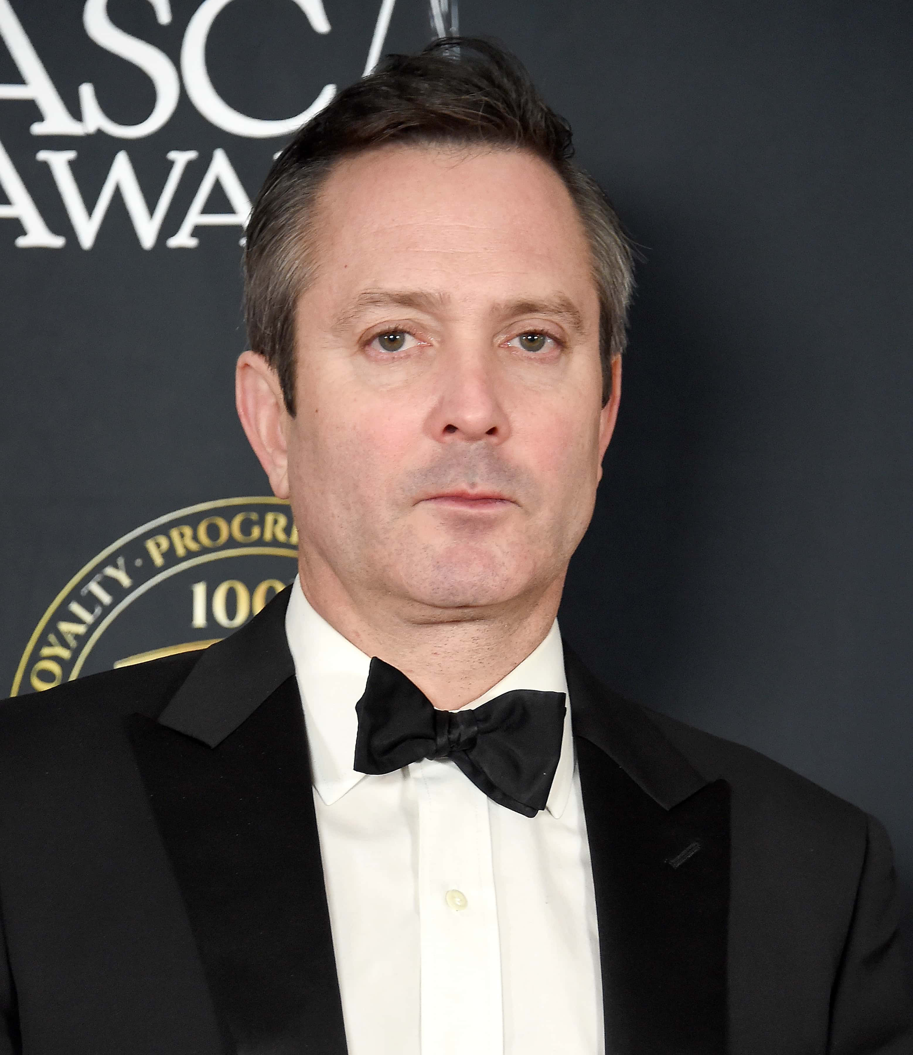 thomas lennon 桌布 壁紙 — 一名身穿黑色禮服和領結的男子在帶有ASCAP Awards品牌的深色背景前正式擺姿勢。