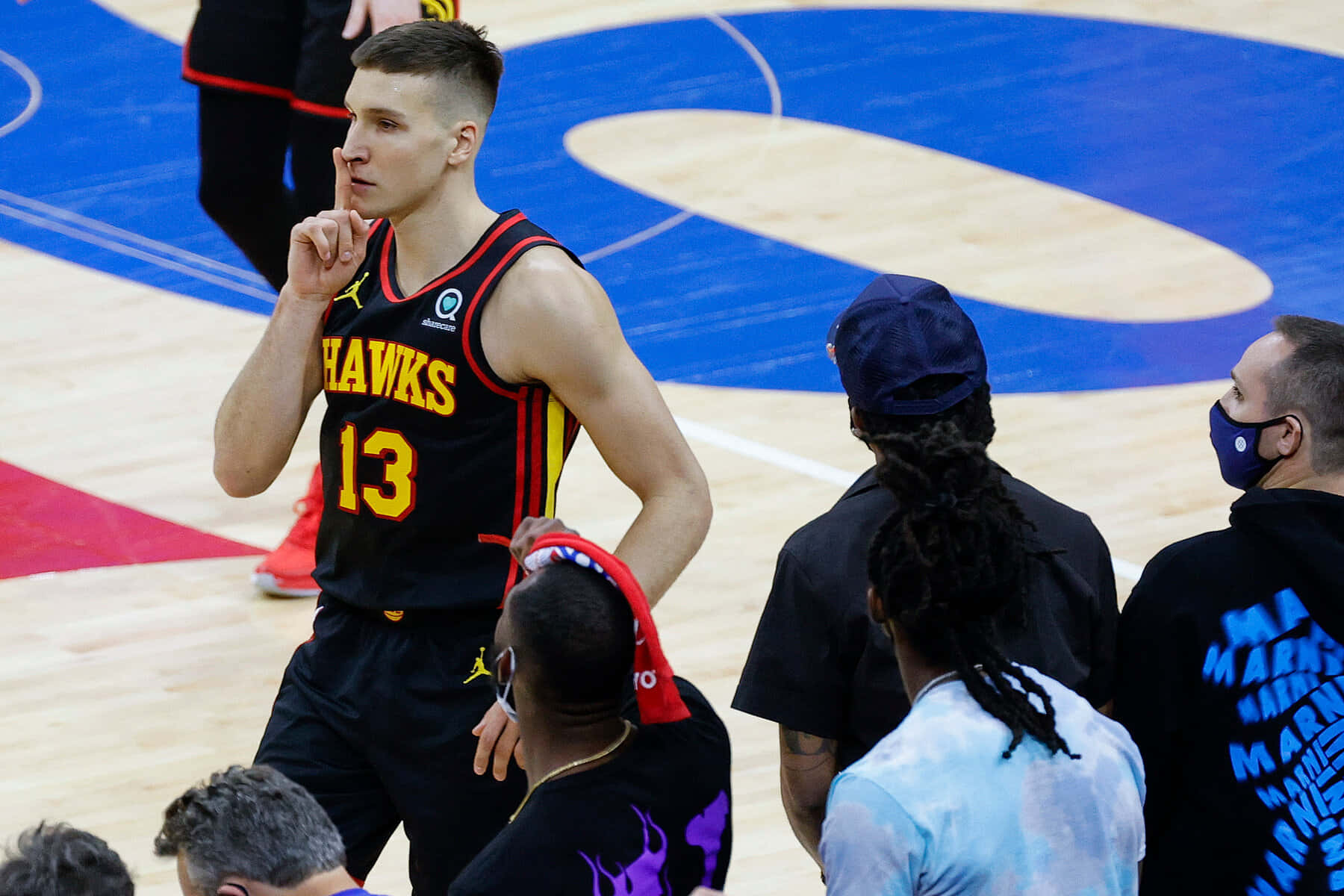 NBA 桌布 壁紙 — 一名身穿黑色老鷹隊13號球衣的籃球運動員站在球場上，手指放在嘴唇上，被隊友和工作人員包圍。