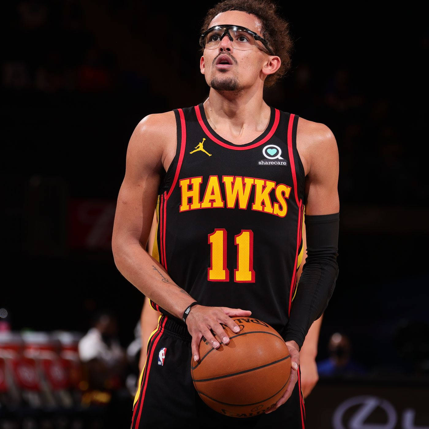 Trae Young 桌布 壁紙 — 一名身穿黑色老鷹隊球衣、背號11的籃球運動員在場館燈光下持球。