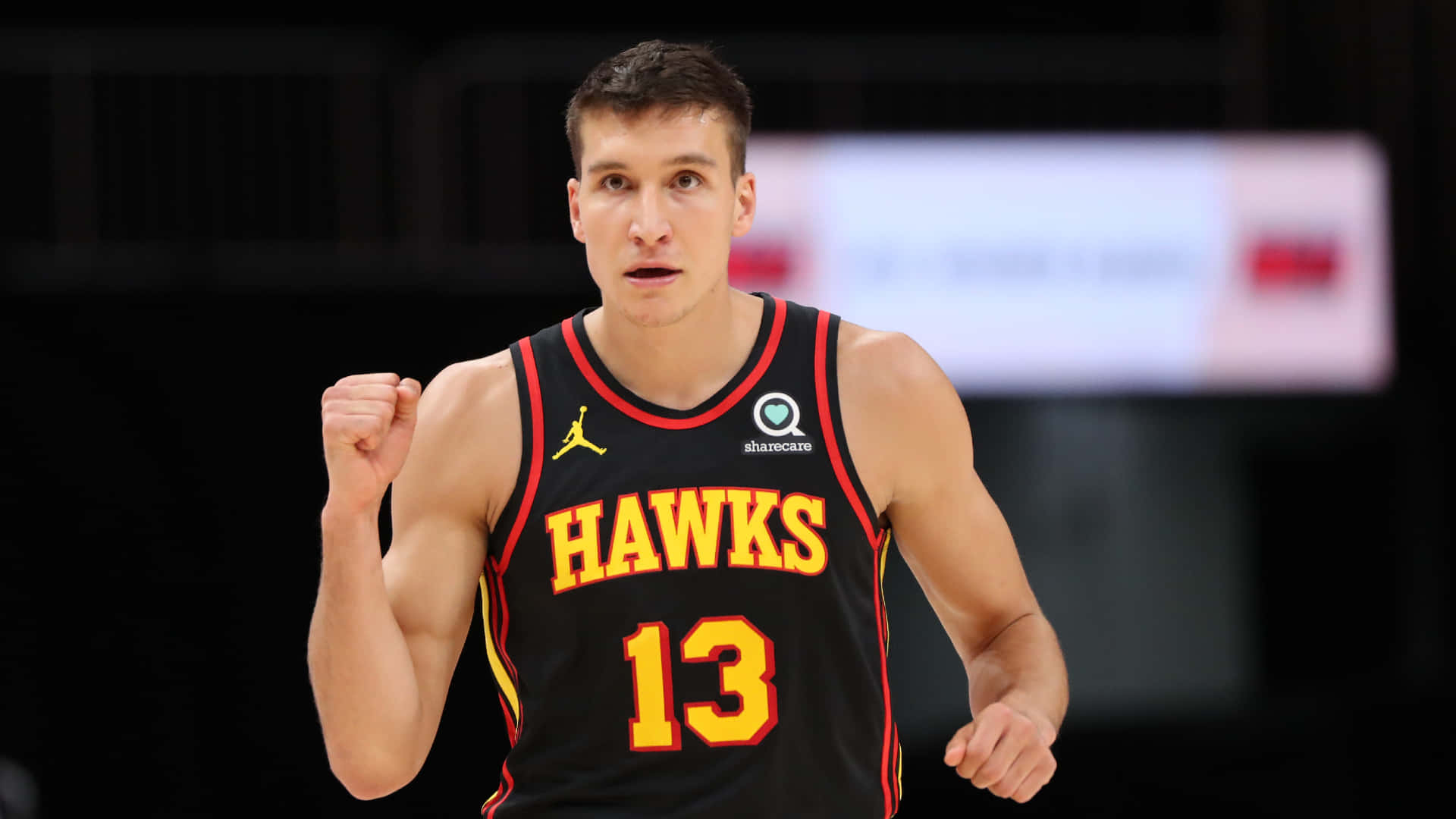 NBA 桌布 壁紙 — 一名身穿黑色老鷹隊球衣、號碼13的籃球運動員在明亮的場館燈光下，比賽中緊握拳頭。