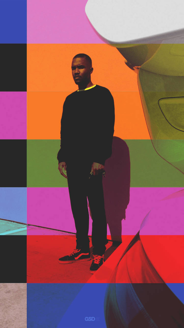 Frank Ocean 桌布 壁紙 — 一名身穿黑色衣服的男子站在充滿活力的幾何背景前，背景由大膽的彩色方塊和抽象形狀組成。