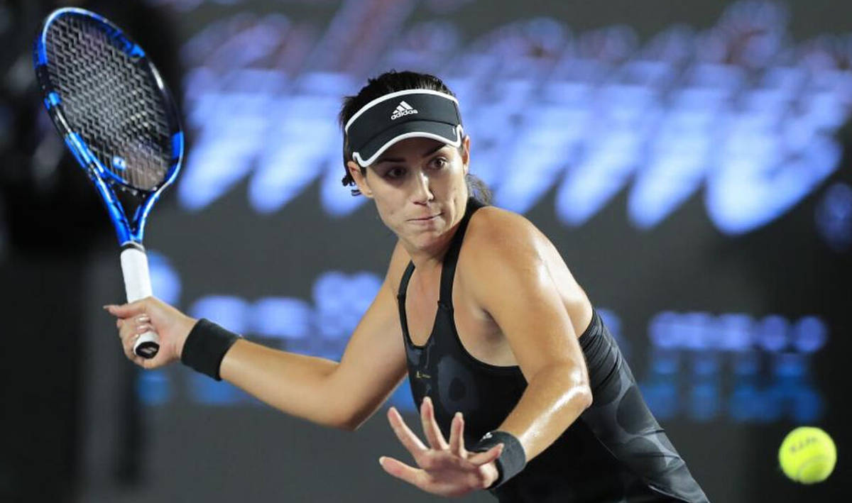 Tennis 桌布 壁紙 — 一名身穿黑色裝備的女網球選手在明亮的體育場燈光下揮動藍色球拍擊打黃色球。