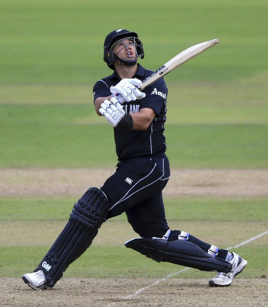 Ross Taylor 桌布 壁紙 — 一名身穿黑色裝備的板球擊球手在明亮的日光下，在綠色場地上強力揮動球棒。