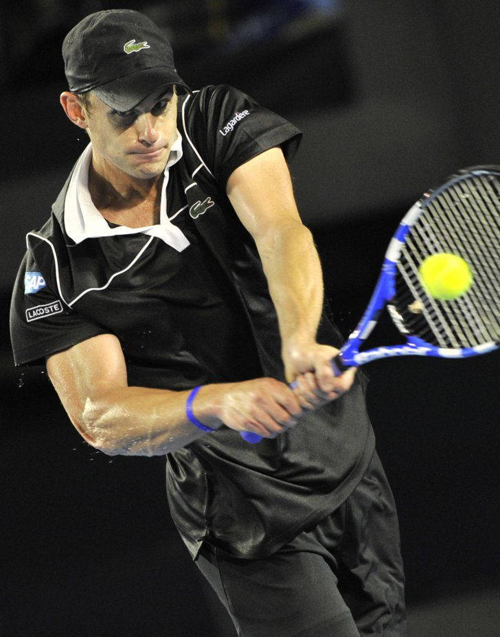 Tennis 桌布 壁紙 — 一名身穿黑色裝備的男網球選手在明亮的場館燈光下揮動藍色球拍擊打黃色網球。