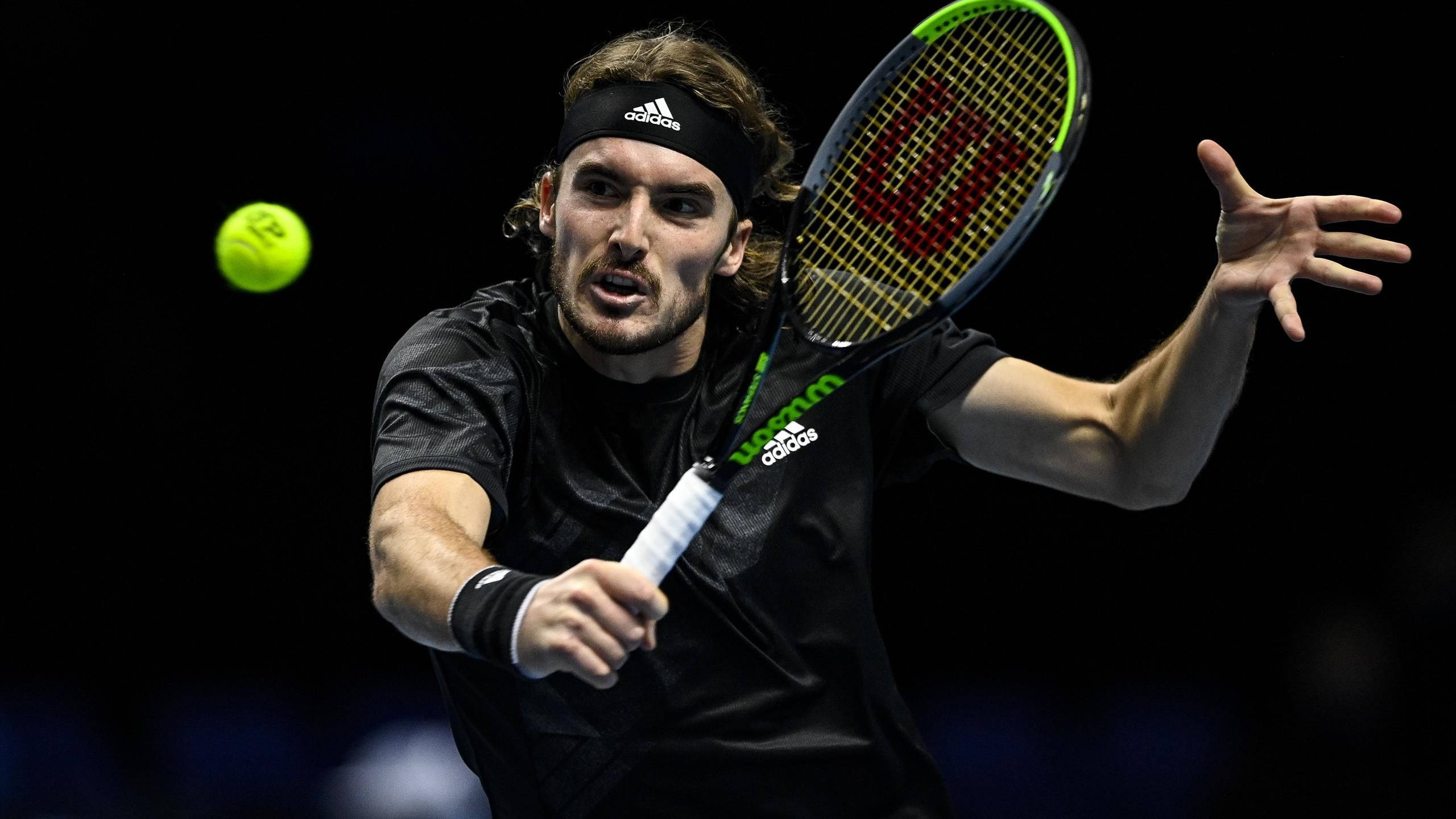 Tennis 桌布 壁紙 — 一名身穿黑色裝備的男網球選手在深色背景下揮拍擊打一個亮黃色的球。