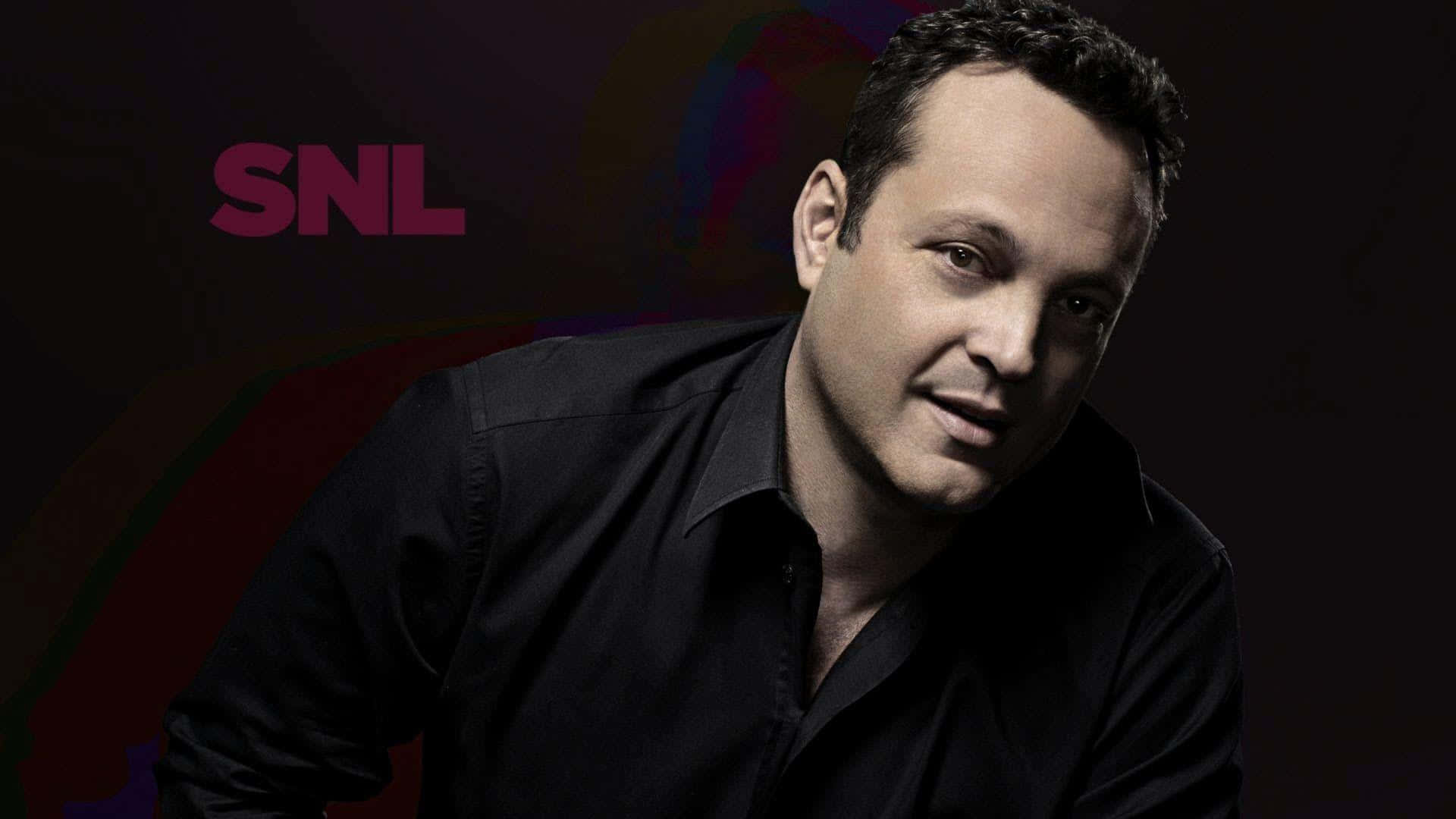 Vince Vaughn 桌布 壁紙 — 一名身穿黑色襯衫的男子在深色背景前擺姿勢，背景有色彩繽紛的抽象漩渦和洋紅色的SNL標誌。