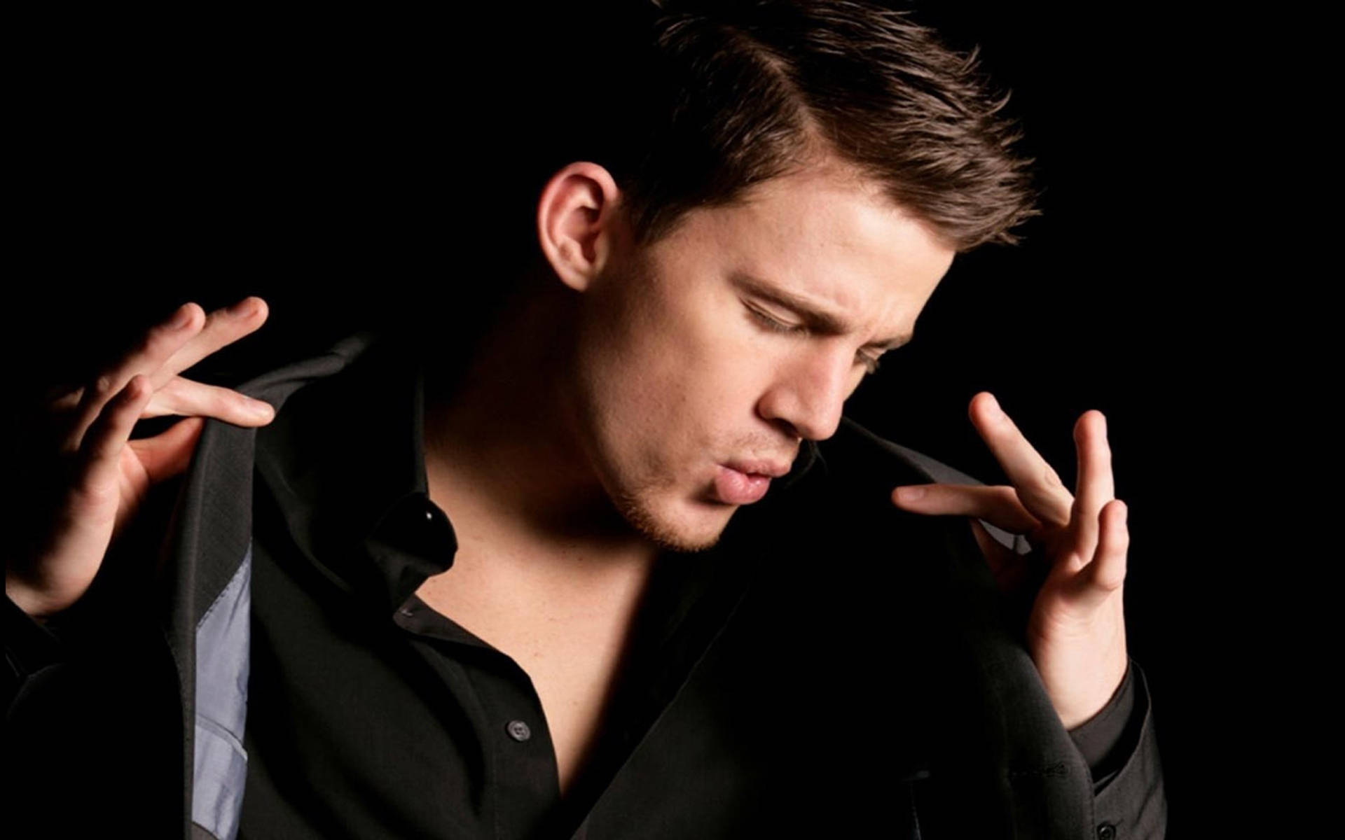 Channing 桌布 壁紙 — 一名身穿黑色襯衫的男子在深色背景前用雙手做出和平手勢。