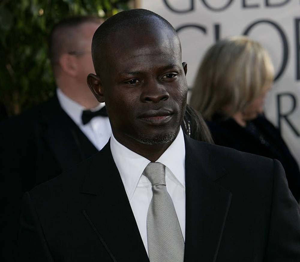 Celebrity 桌布 壁紙 — 一名身穿黑色西裝和灰色領帶的男子，在身後有「金球獎」標誌的紅地毯活動上莊嚴地站立。