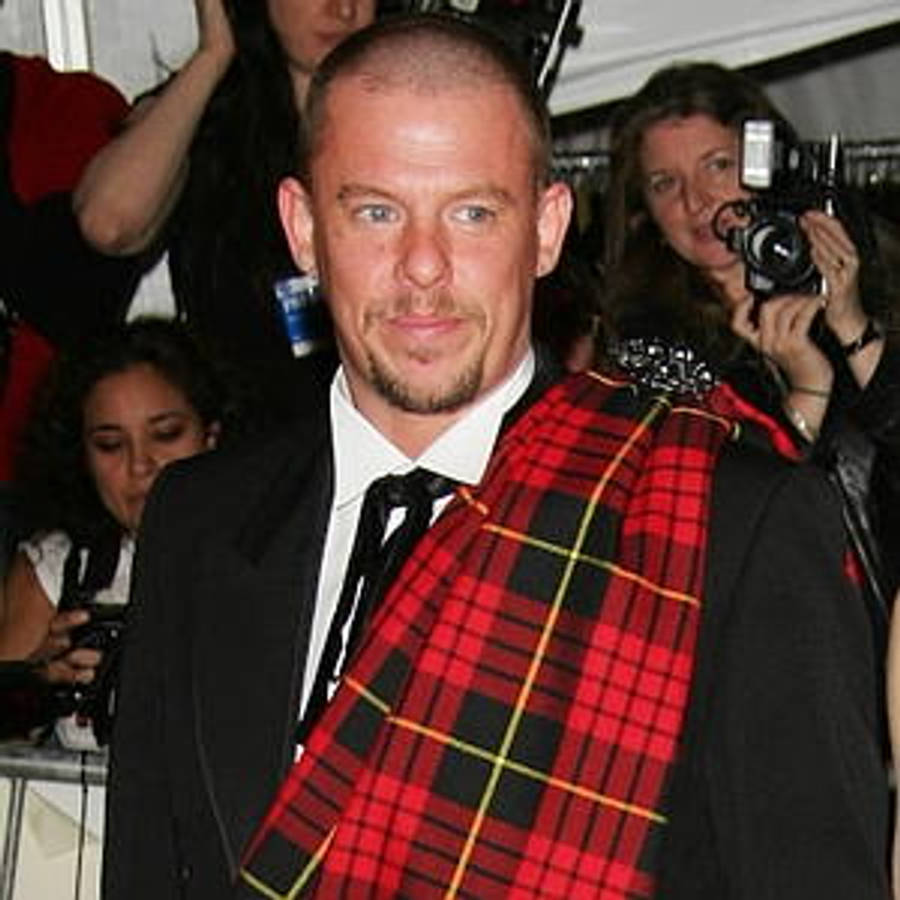 artist 桌布 壁紙 — 一名身穿黑色西裝和紅色格紋圍巾的男子在活動中對著鏡頭微笑，攝影師們正在捕捉他的身影。