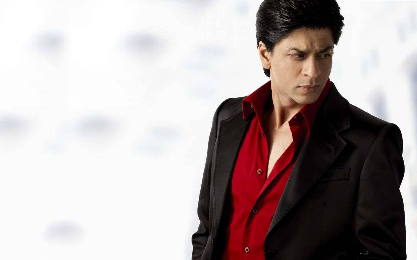Shahrukh 桌布 壁紙 — 一名身穿黑色西裝和紅色襯衫的男子，站在明亮的白色模糊背景前，表情嚴肅。