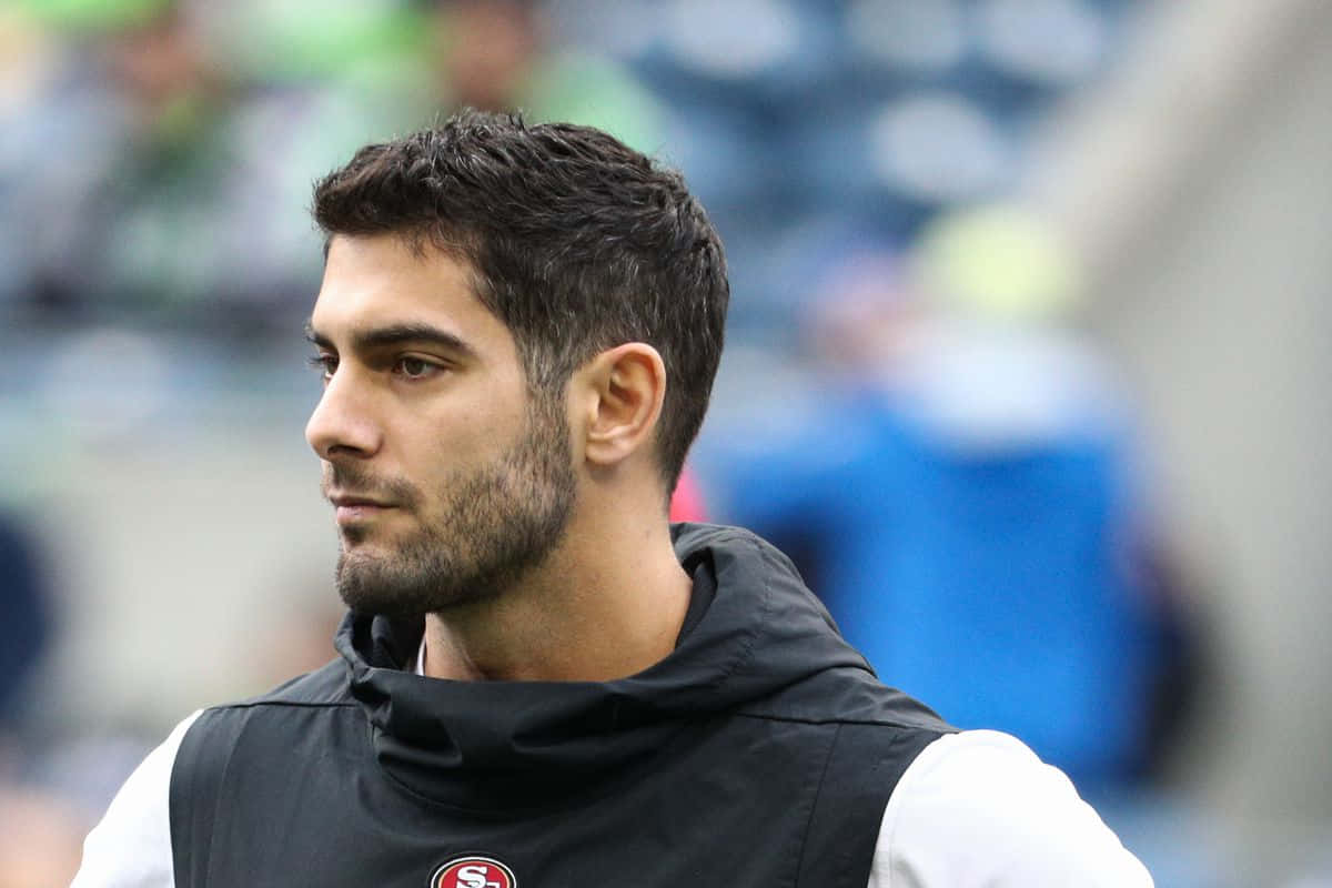 Jimmy Garoppolo 桌布 壁紙 — 一名身穿黑色訓練背心的專注足球運動員在日間球場訓練中凝視著。