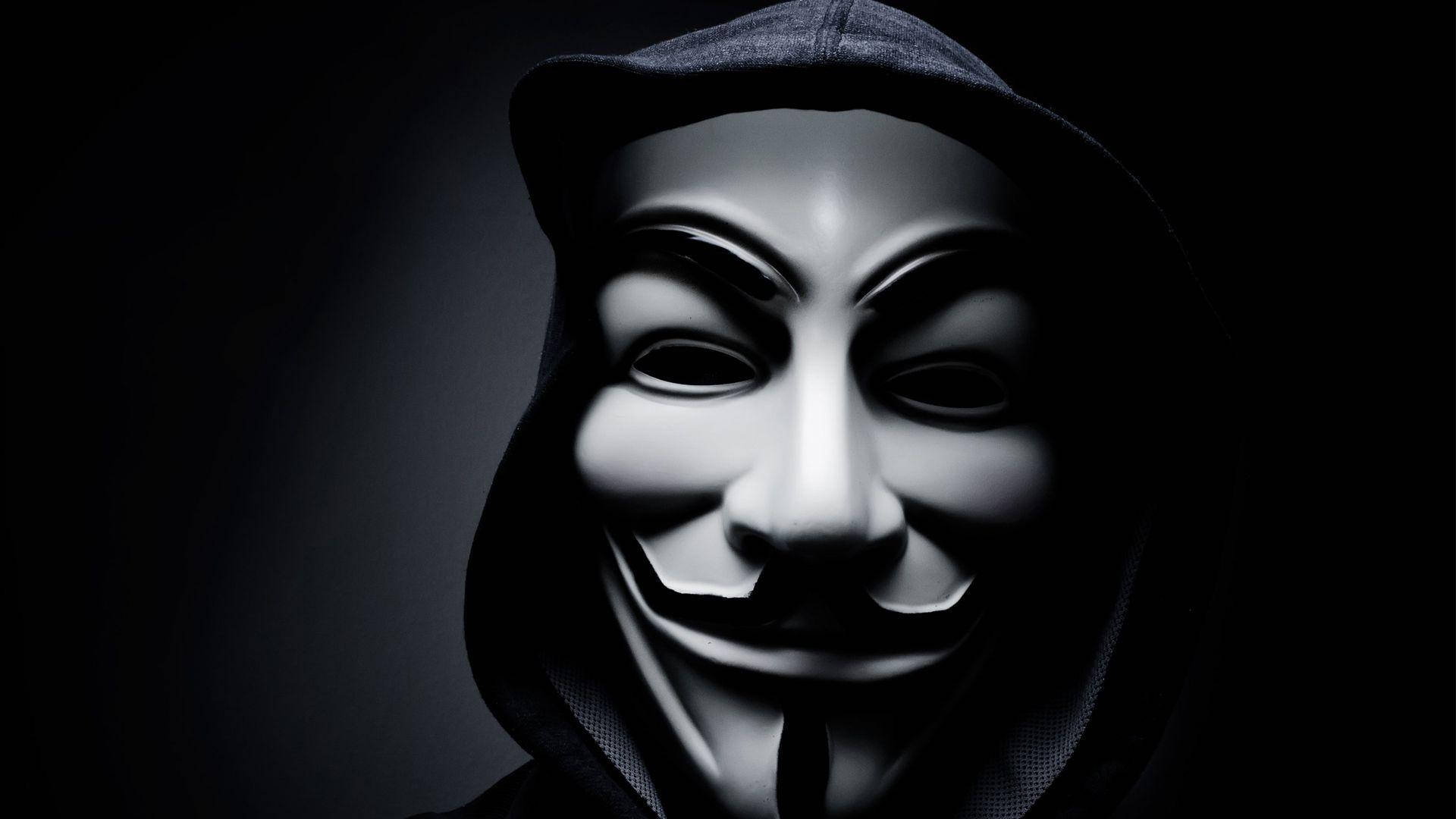 Hacker Full HD 桌布 壁紙 — 一名身穿黑色連帽衫的人，在深色漸變背景前戴著白色蓋伊·福克斯面具。