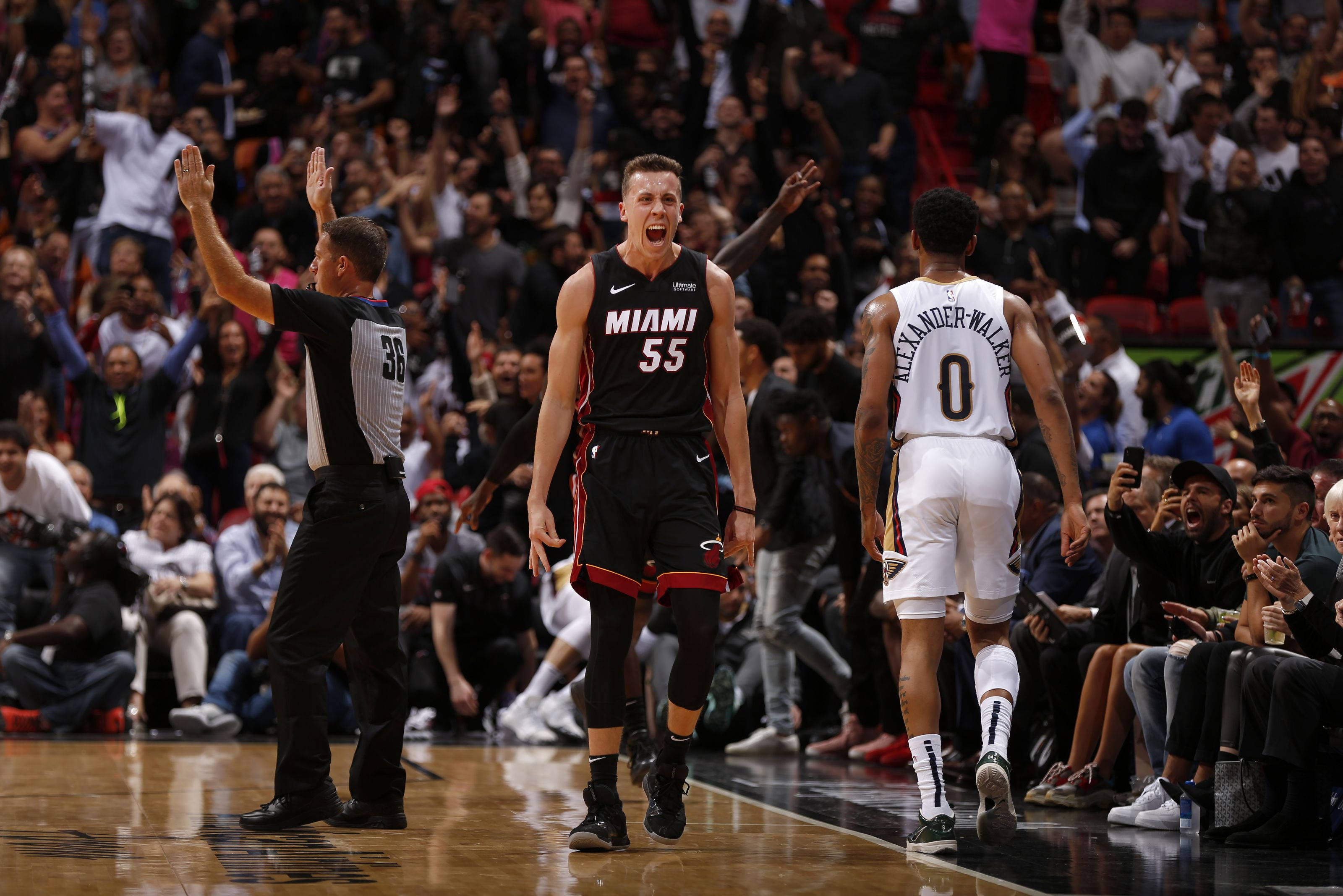 duncan robinson 桌布 壁紙 — 一名身穿黑色邁阿密球衣的籃球運動員在裁判舉起雙手、另一名球員在擁擠的球場上走開時，發出勝利的吶喊。