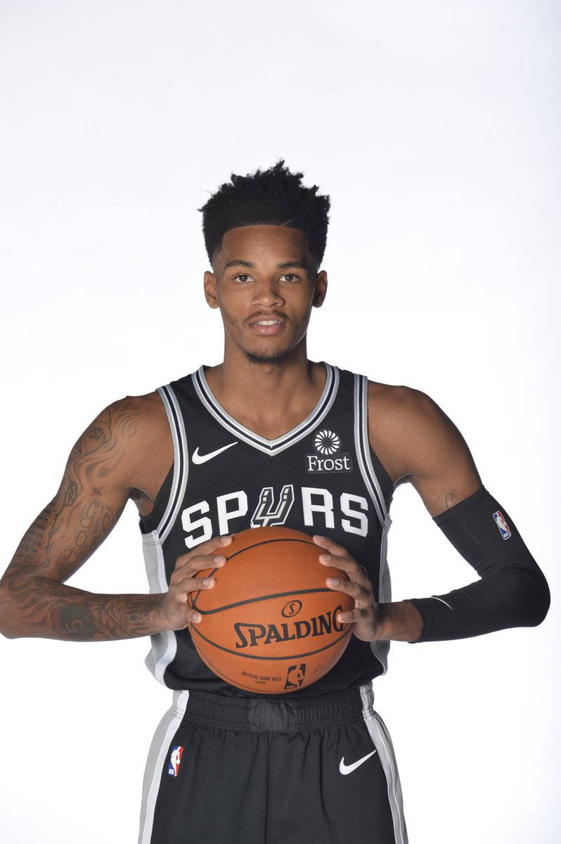 Dejounte Murray 桌布 壁紙 — 一名身穿黑色馬刺球衣的籃球運動員，在純白色背景前拿著一個Spalding籃球。