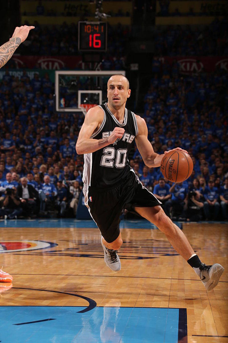 Manu 桌布 壁紙 — 一名身穿黑色馬刺球衣的籃球運動員在拋光硬木球場上衝刺運球，背景是擠滿的人群。