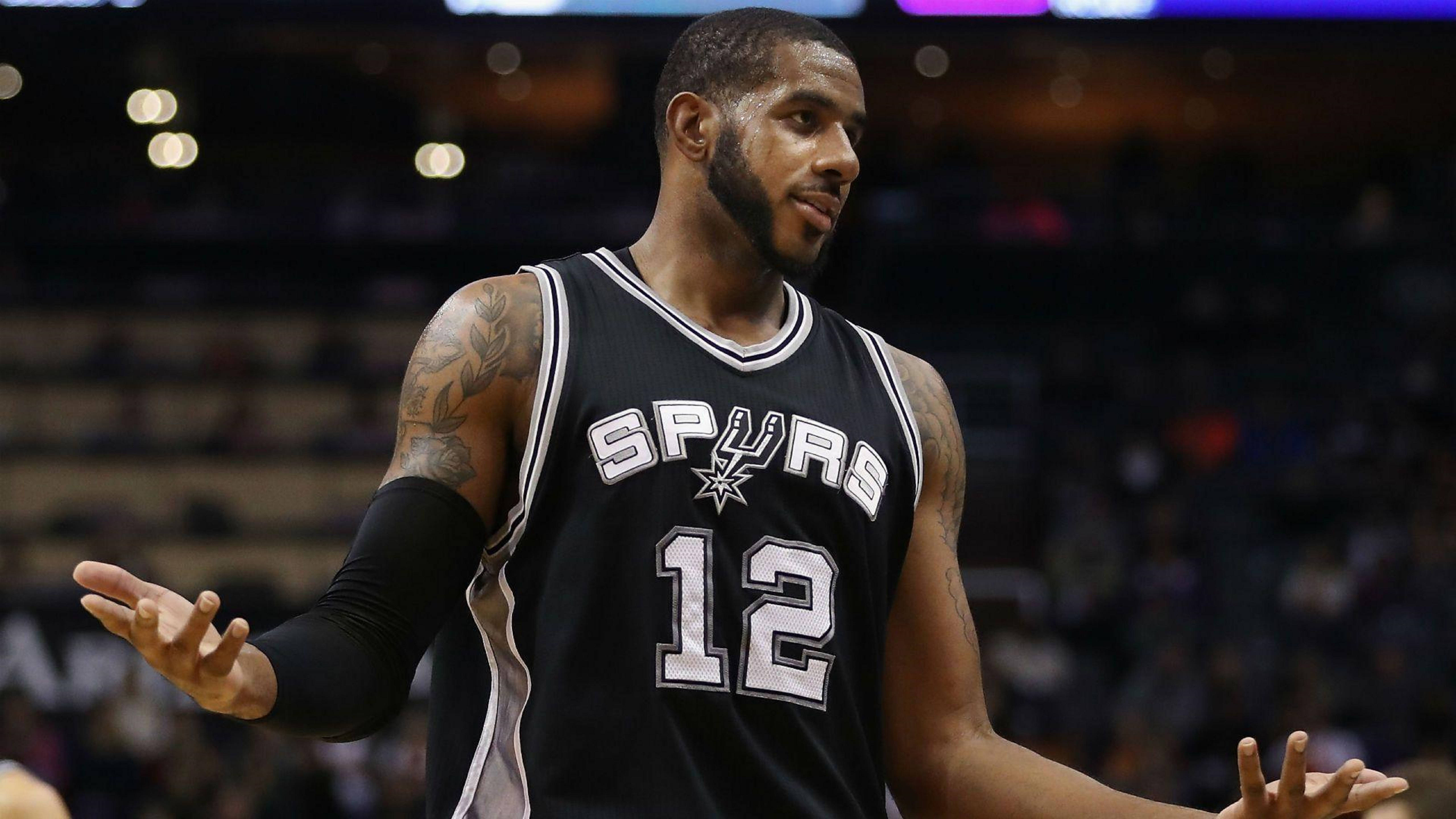 Lamarcus Aldridge 桌布 壁紙 — 一名身穿黑色馬刺隊12號球衣的籃球運動員在場館燈光下比賽時雙手做手勢。