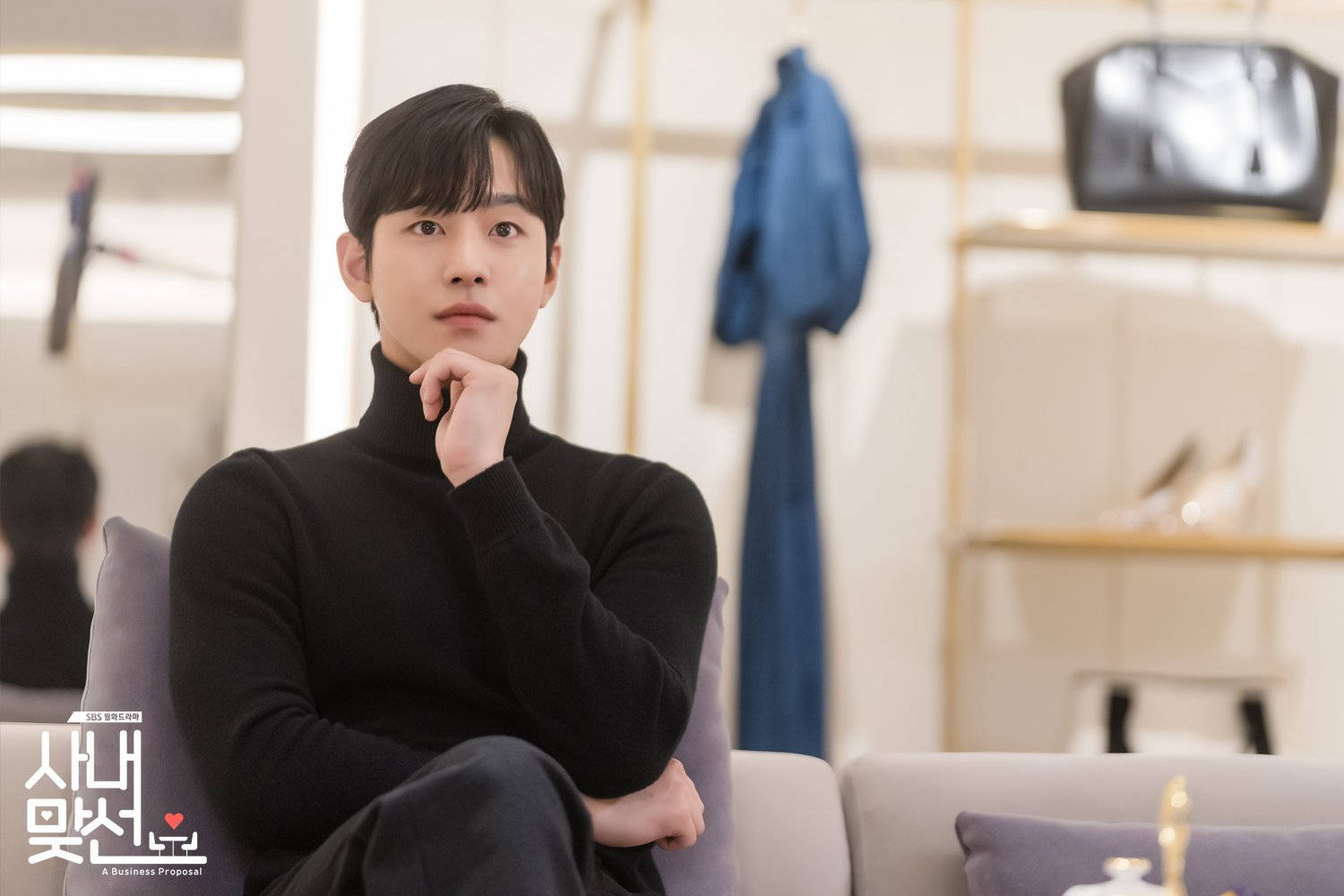 Proposal 桌布 壁紙 — 一名身穿黑色高領毛衣的男子在柔和燈光的現代簡約客廳中沉思地坐在沙發上。