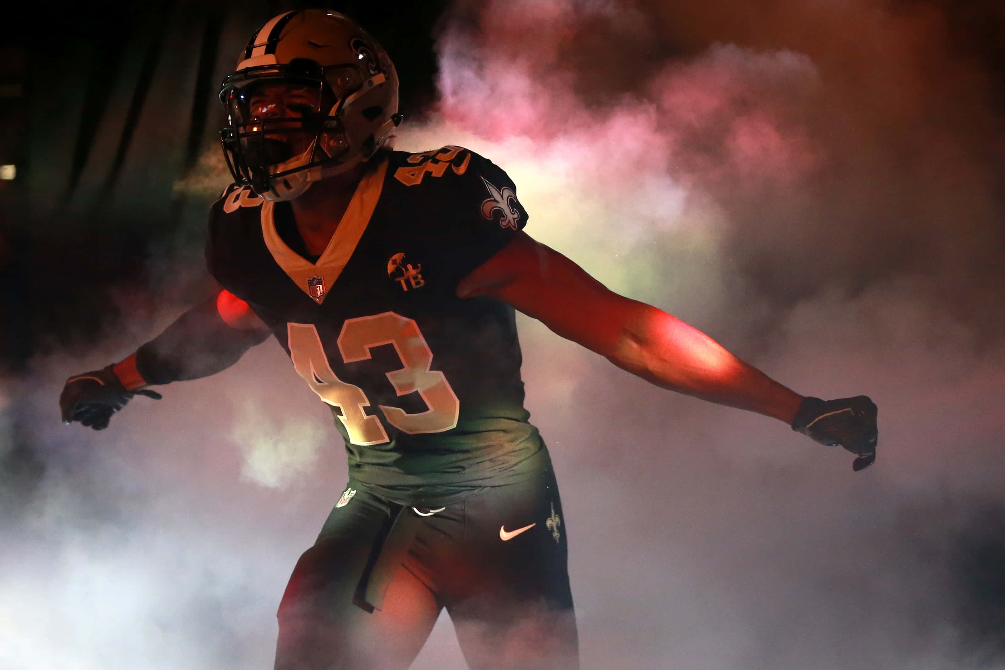 Marcus Williams 桌布 壁紙 — 一名身穿黑金色制服的美式足球員在戲劇性的紅光下從煙霧中出現。