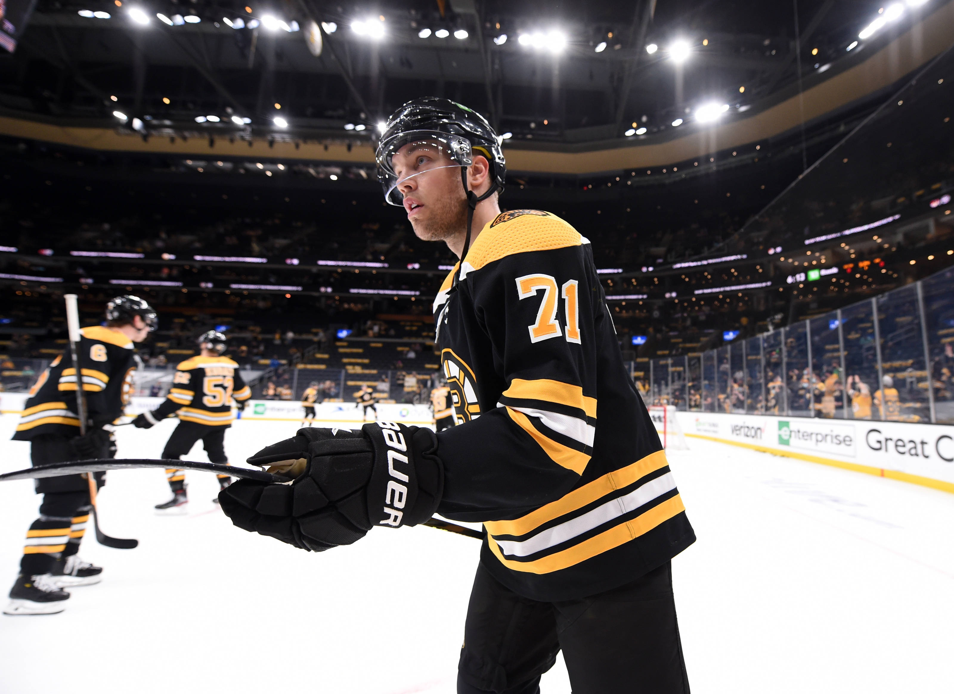 hockey 桌布 壁紙 — 一名身穿黑金色球衣的冰球運動員在明亮的場館燈光下，在冰場上凝視著。