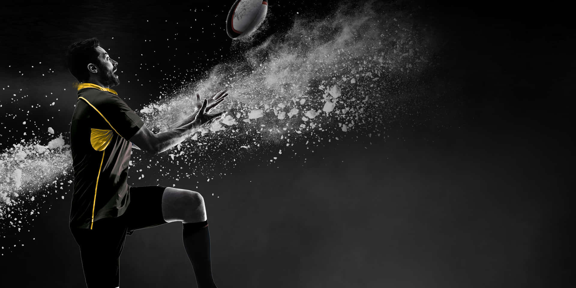Best Sports 桌布 壁紙 — 一名身穿黑黃色球衣的橄欖球運動員踢球，白色粉末在黑暗背景中戲劇性地慢動作爆炸。