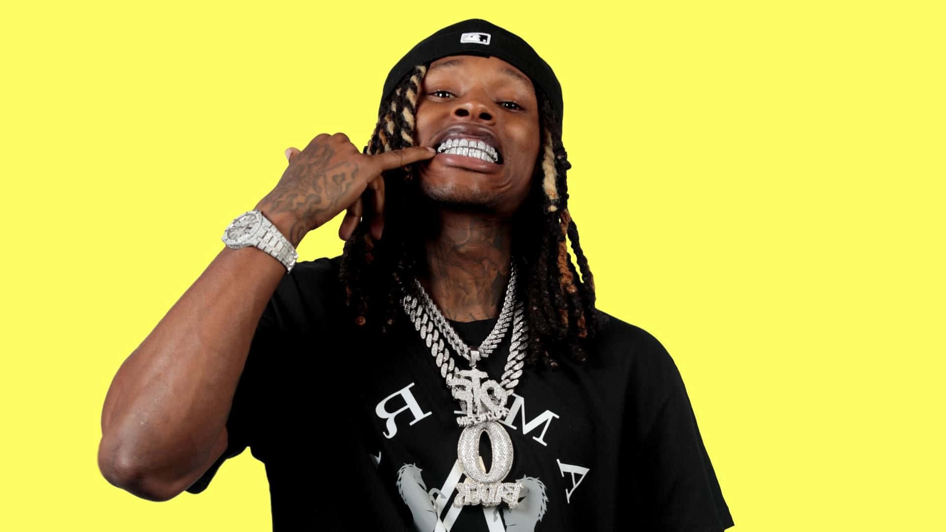 Rapper Pc 桌布 壁紙 — 一名辮子頭髮、戴金鏈的男子在亮黃色背景前自信地擺姿勢。