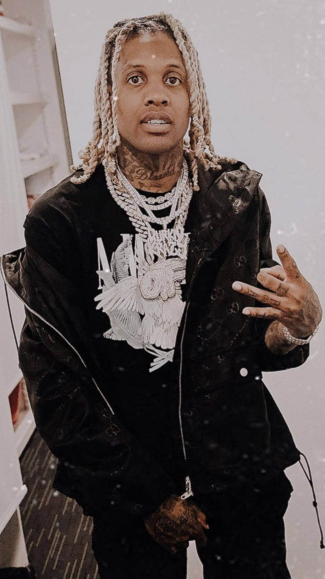Lil Durk 桌布 壁紙 — 一名辮髮紋身男子身穿帶銀鏈的黑色外套，在室內做出手勢。