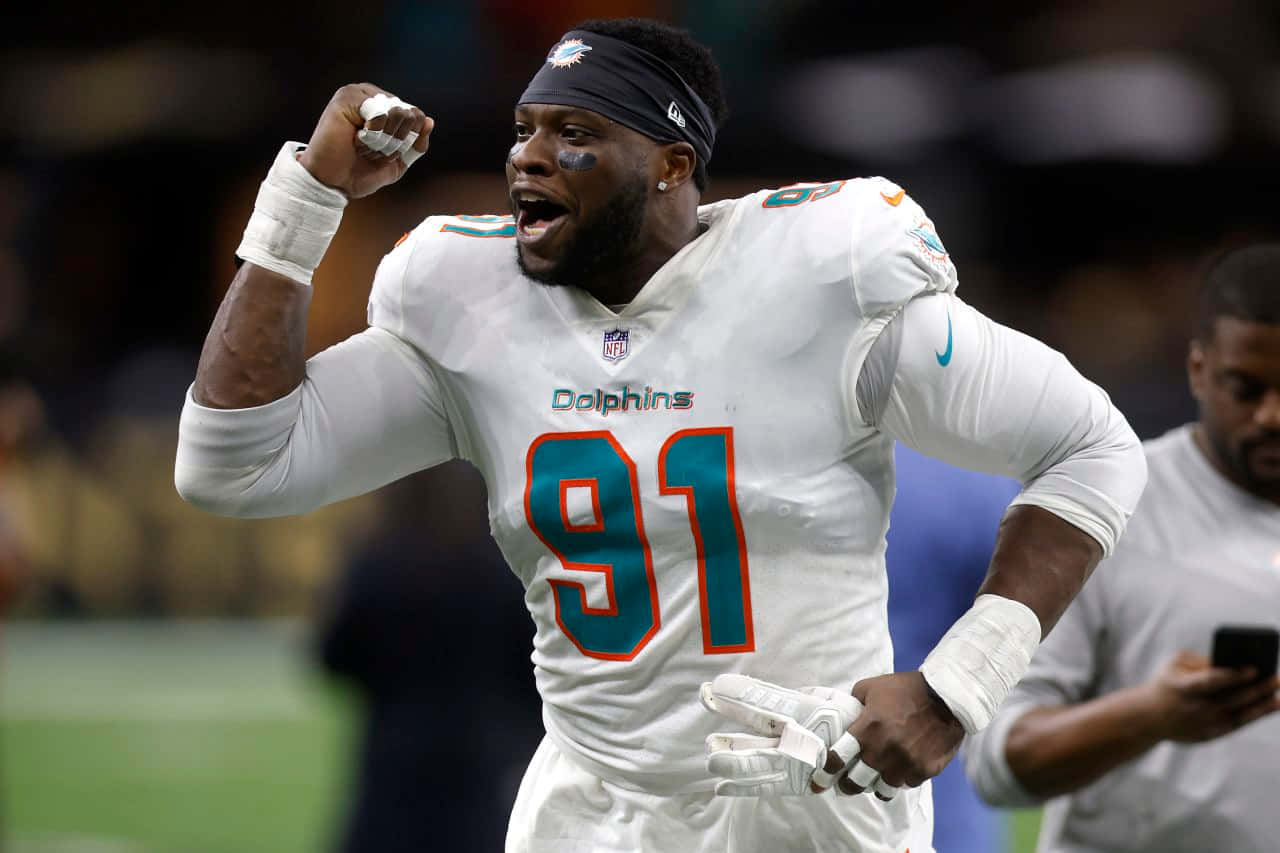 NFL 桌布 壁紙 — 一名邁阿密海豚隊的美式足球員身穿白色91號球衣在球場上舉拳慶祝。