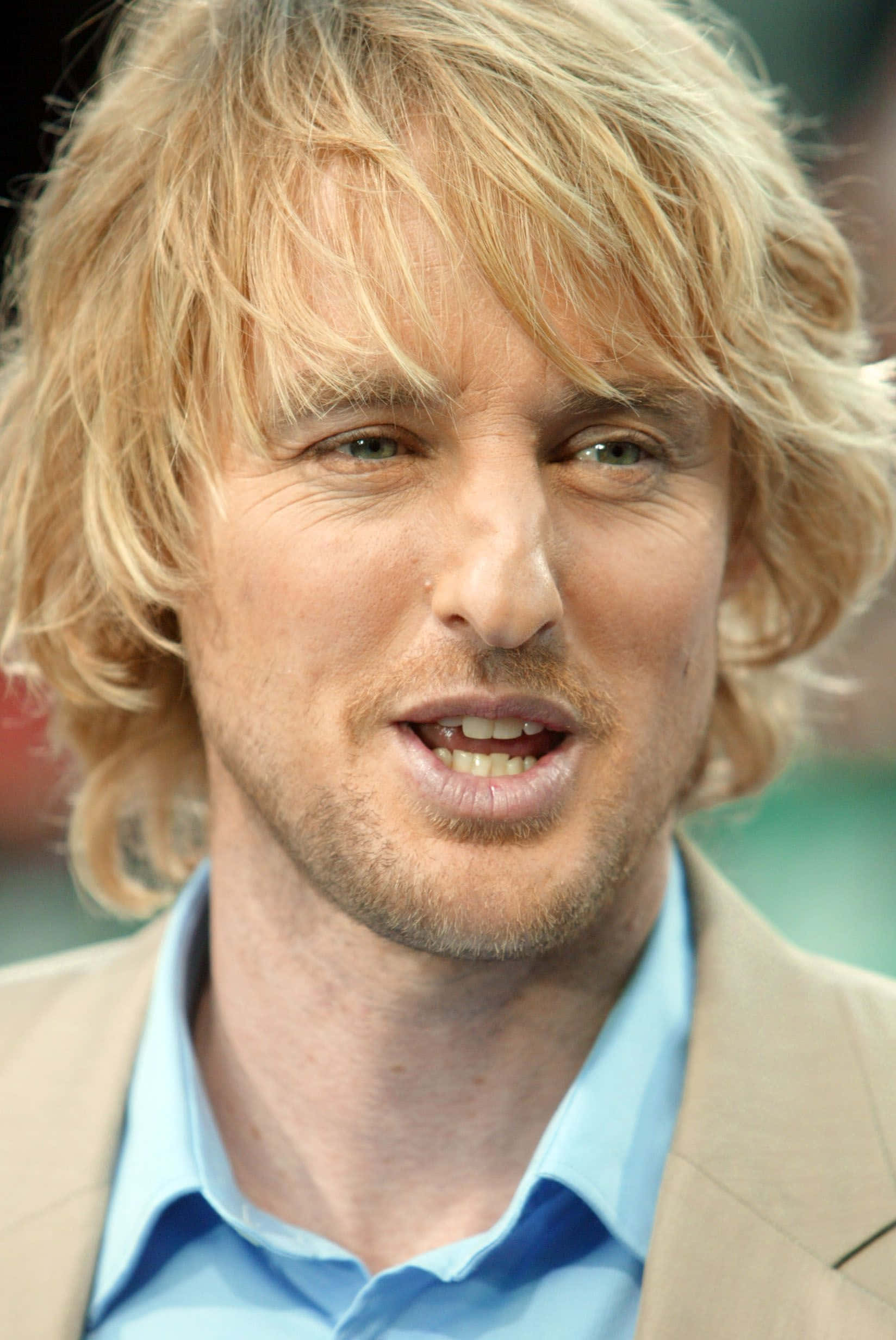 Owen Wilson 桌布 壁紙 — 一名金髮凌亂、留著淺鬍鬚的男士的頭像特寫，身穿米色西裝外套內搭藍色襯衫。