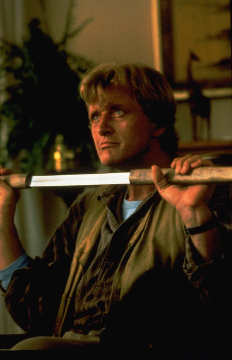 actor 桌布 壁紙 — 一名金髮男子在溫暖照明的室內環境中將劍橫跨在肩膀上。