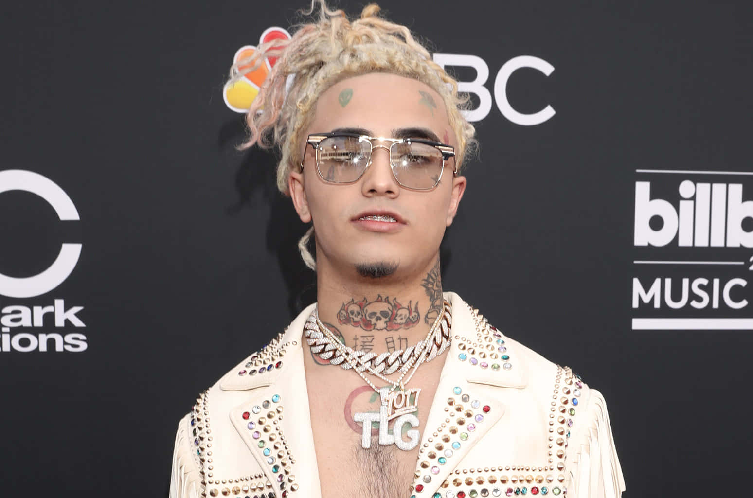 桌布 壁紙 — 一名金髮辮子、戴太陽眼鏡的男子，在Billboard音樂獎紅地毯活動中穿著飾有鉚釘的白色外套。